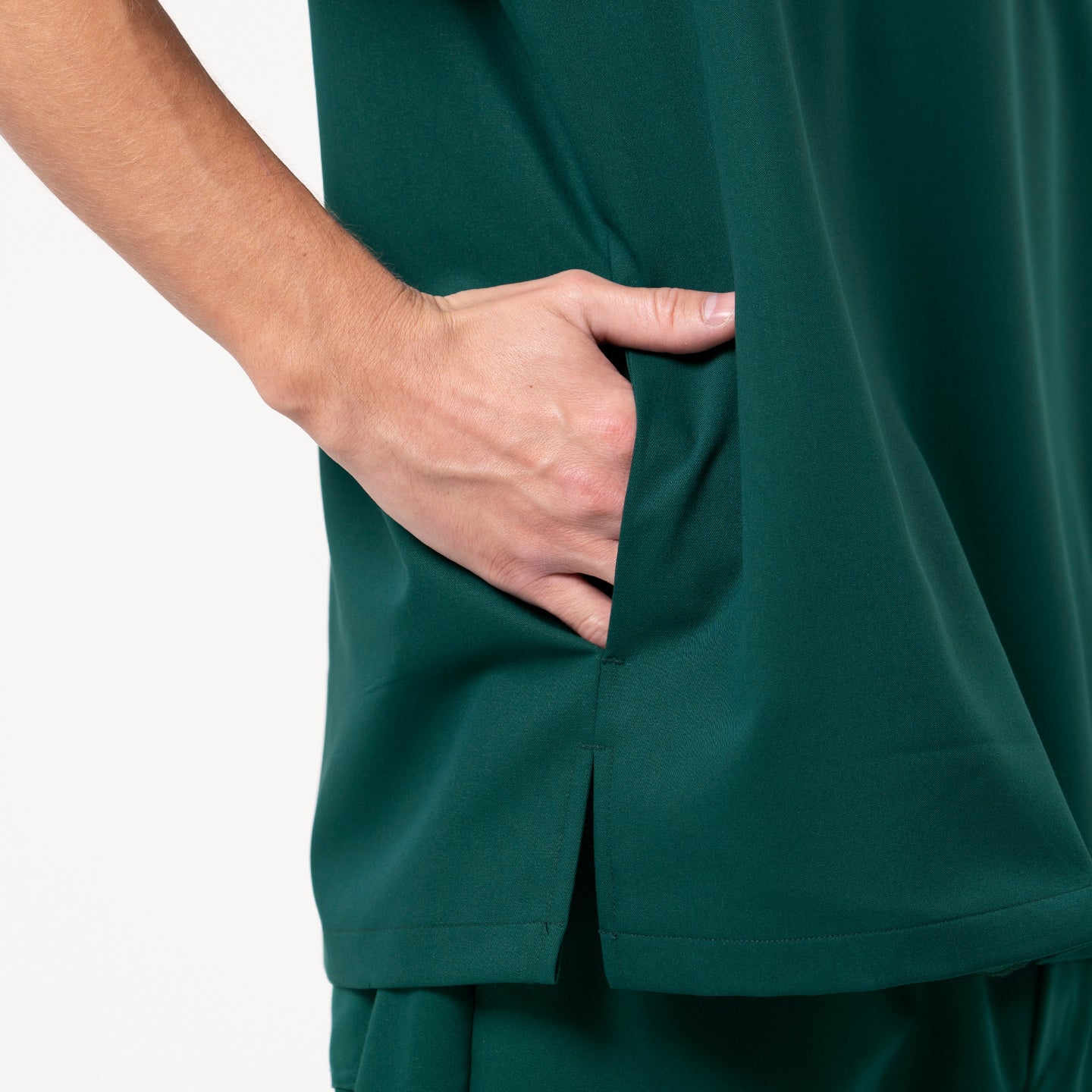 Close-up of a Pine Green scrub top, showing a model’s hand placed inside the side pocket.