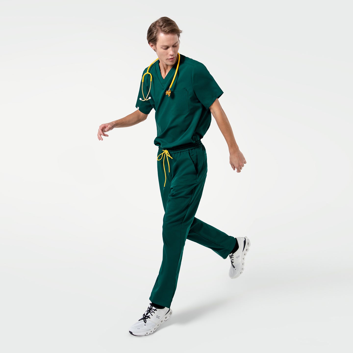 Image of A walking model in Pine Green 3 Pocket Scrub Top strikes a dynamic pose with a focused expression.
