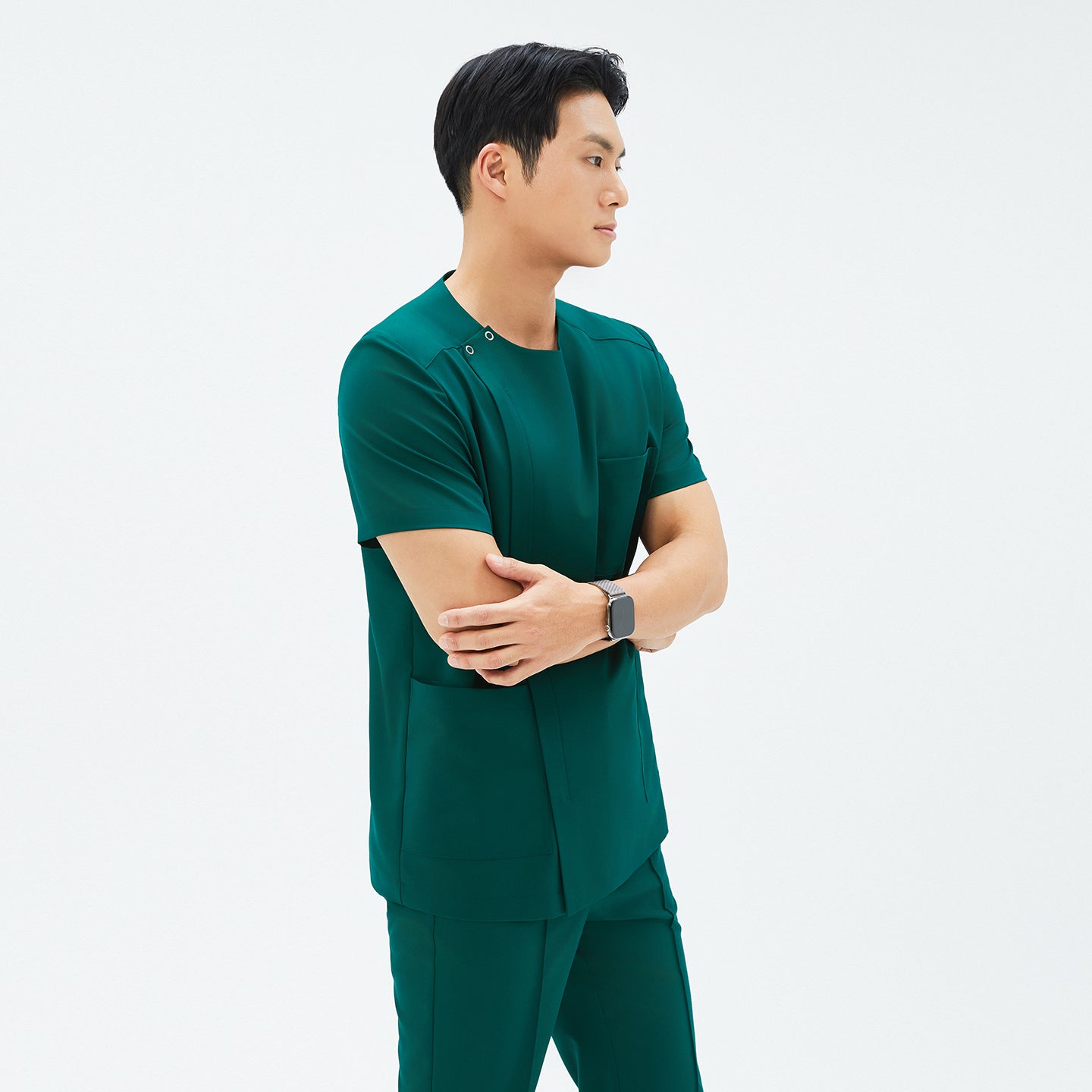 Model crossing arms in TUL DS-191 Men's Round Snap Zipper Scrub Top in Pine Green, highlighting the snap collar and sleek, tailored fit.
