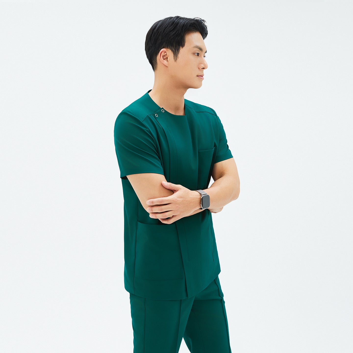 Image of Model crossing arms in TUL DS-191 Men's Round Snap Zipper Scrub Top in Pine Green, highlighting the snap collar and sleek, tailored fit.