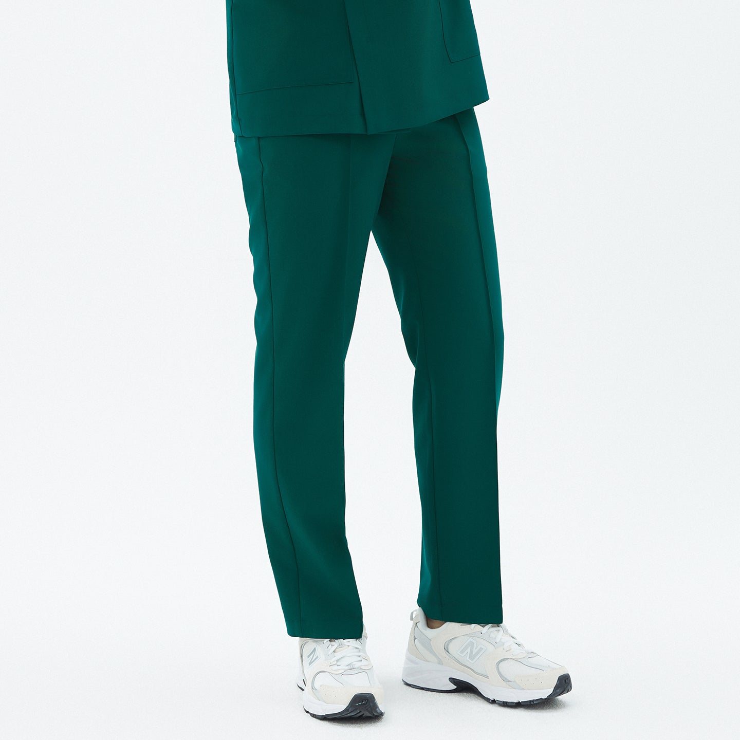 Image of Close-up of TUL Men’s Premium Banding Pants in Pine Green, highlighting the straight-leg design and subtle stretch fabric. The model stands with his arms at his sides.