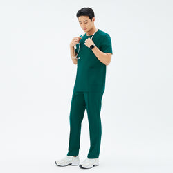 Image of Male model wearing TUL Men’s Premium Banding Pants in Pine Green, standing in a relaxed pose with a stethoscope around his neck. The pants feature polished seams, and the matching scrub top creates a unified professional look.