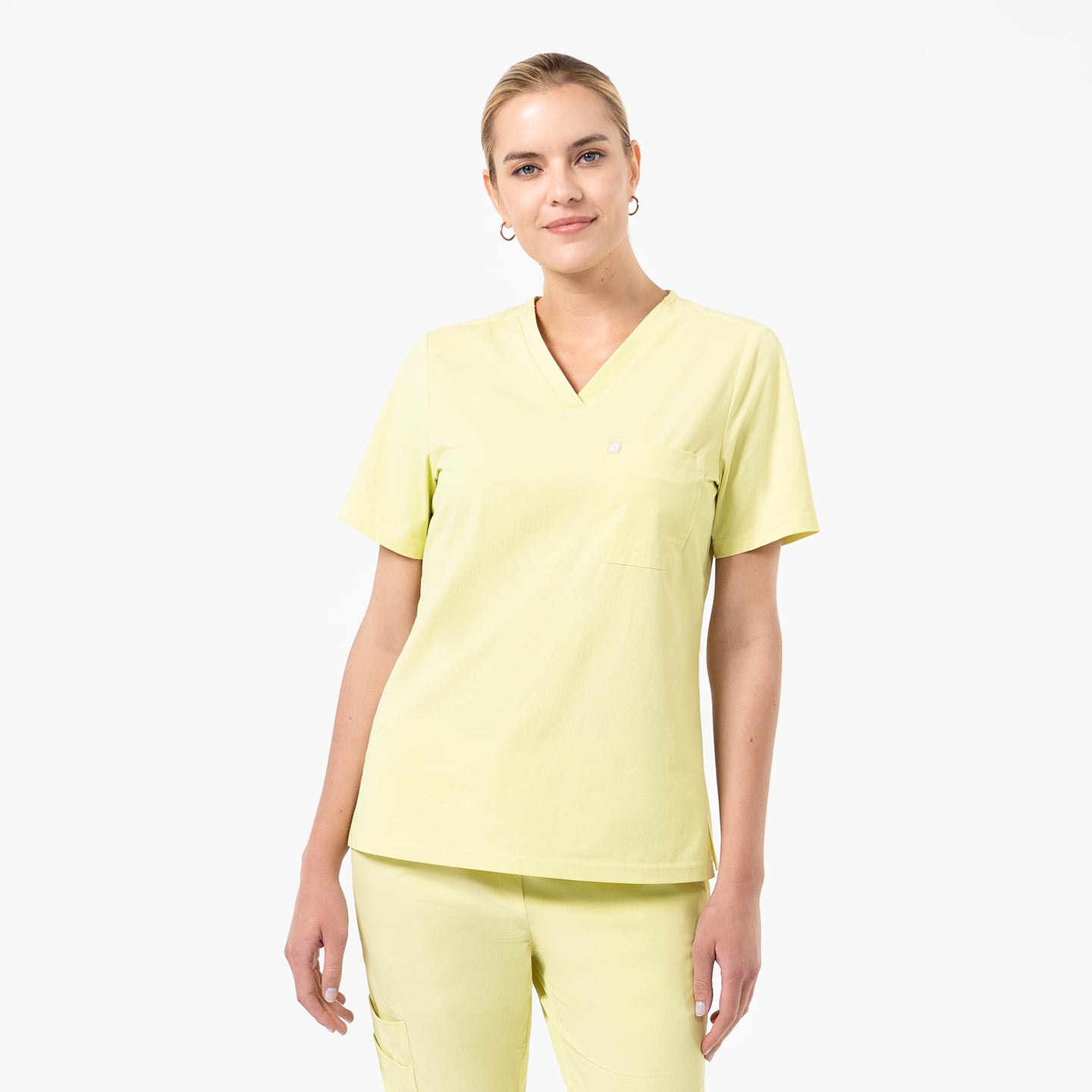 Image of Wearing the Women's Pineapple Yellow Single Pocket Scrub Top with matching pants, facing forward with a slight smile, upper body shot