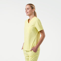 Image of Model in Pineapple Yellow single pocket scrub top with short sleeves and chest pocket, paired with matching scrub pants.