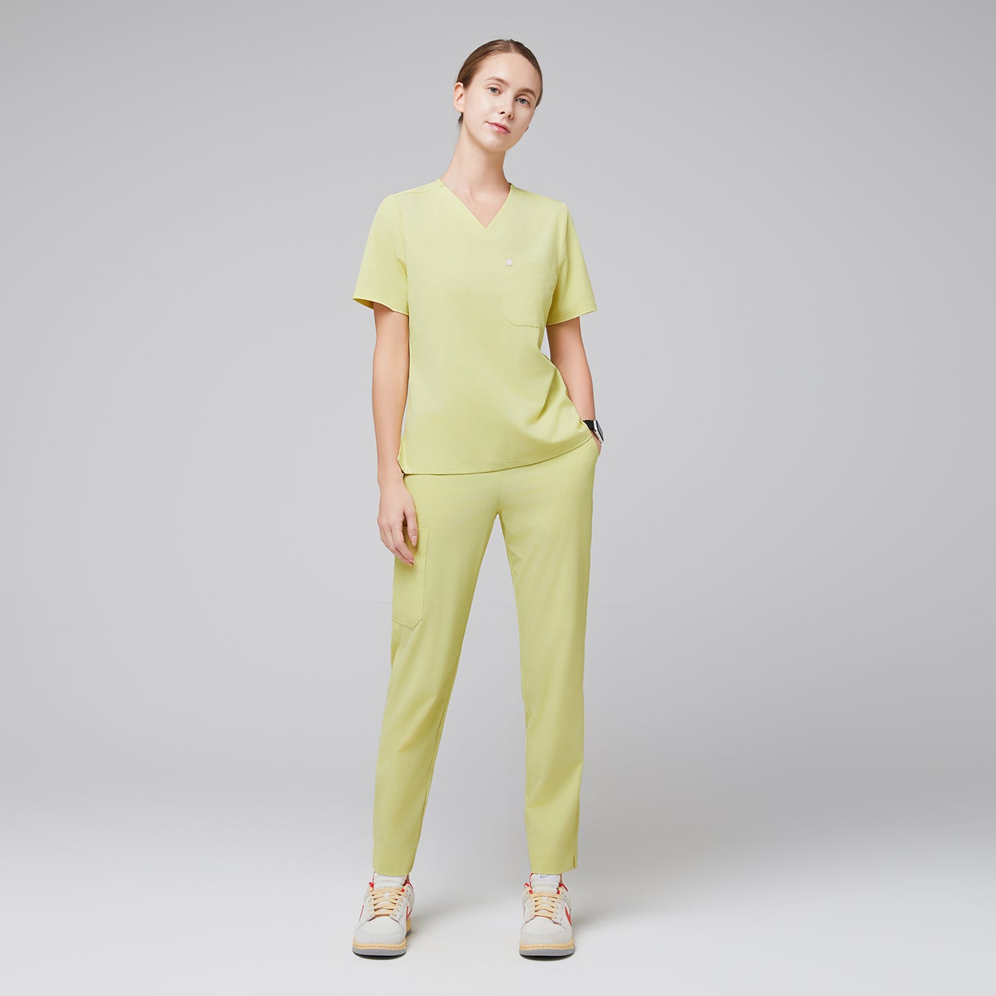 Image of Female wearing pineapple yellow V-neck scrub top and matching pants with beige sneakers,Pineapple Yellow