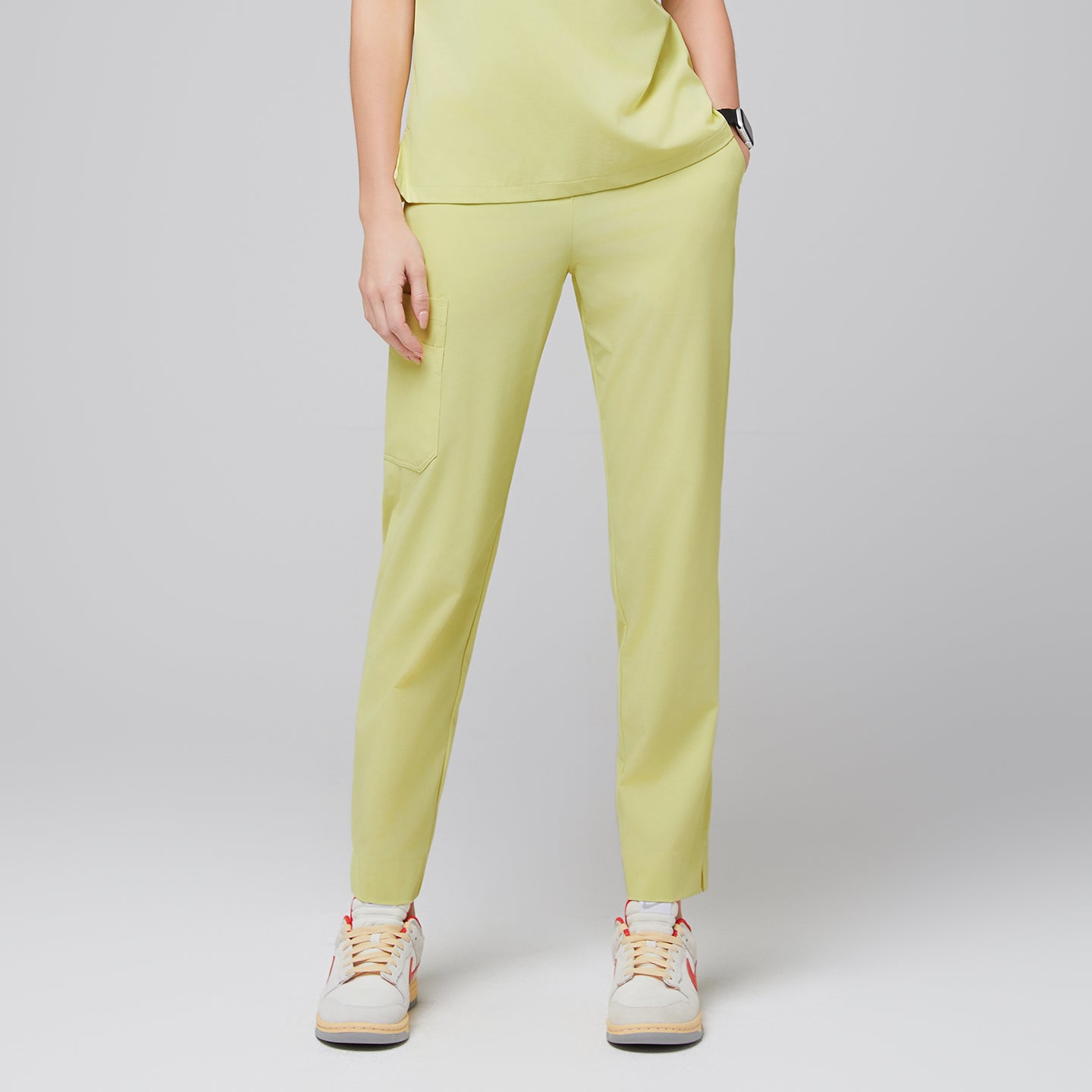 Image of Female wearing pineapple yellow scrub pants with side pocket, paired with beige sneakers,Pineapple Yellow