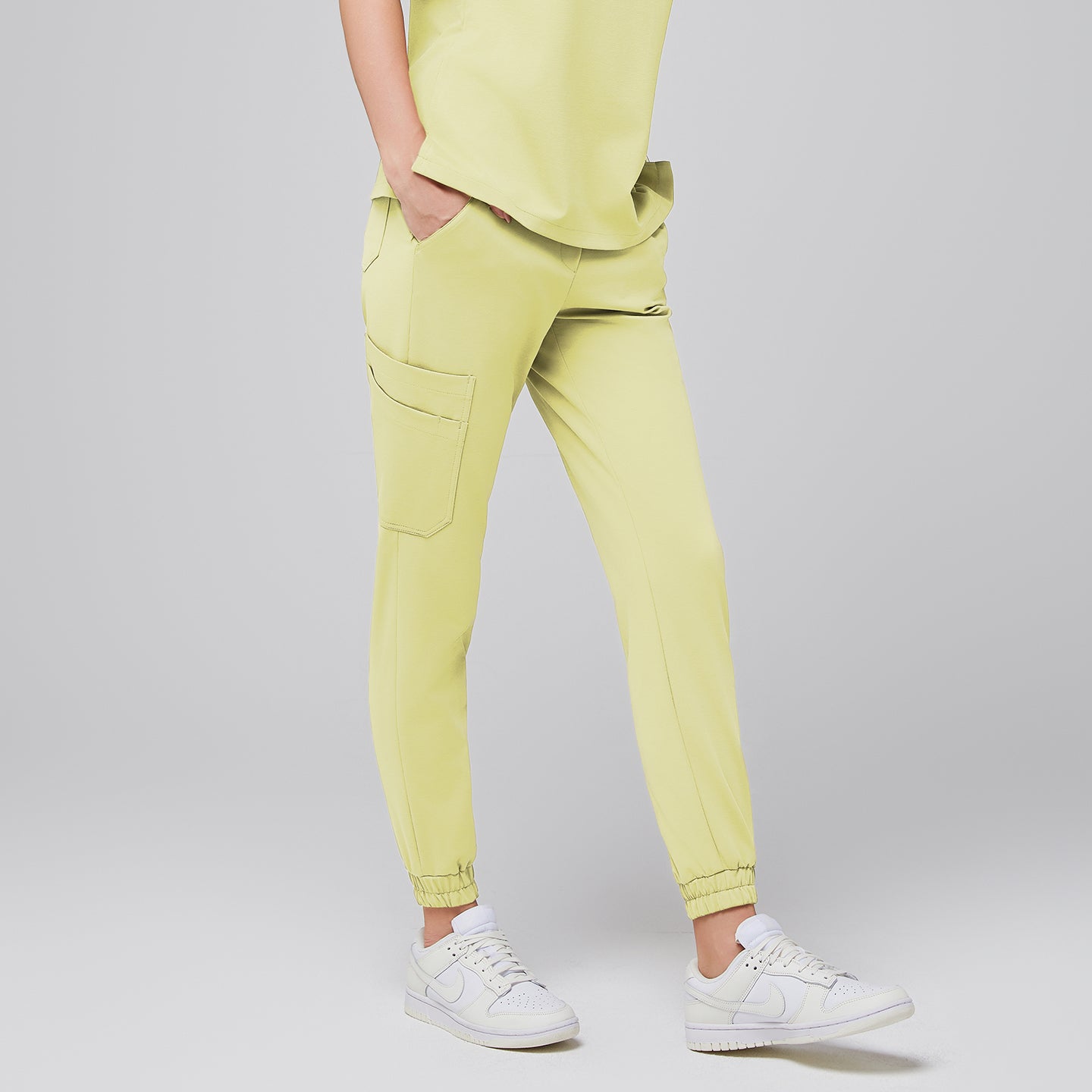 Image of Close-up of light yellow jogger scrub pants with side pockets, worn with white Nike sneakers,Pineapple Yellow
