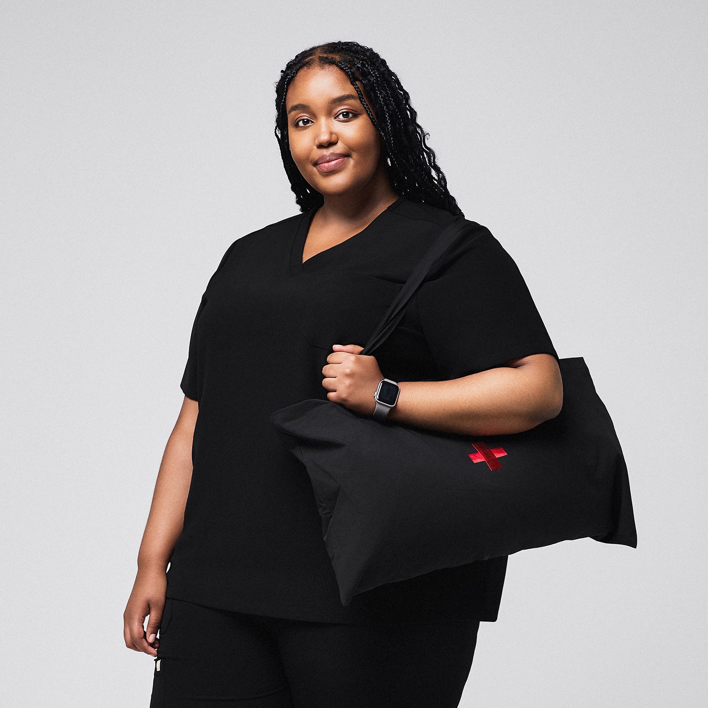Image of Female medical professional wearing a black scrub top, holding a large black bag with a red cross symbol, and smiling confidently,Rich Black
