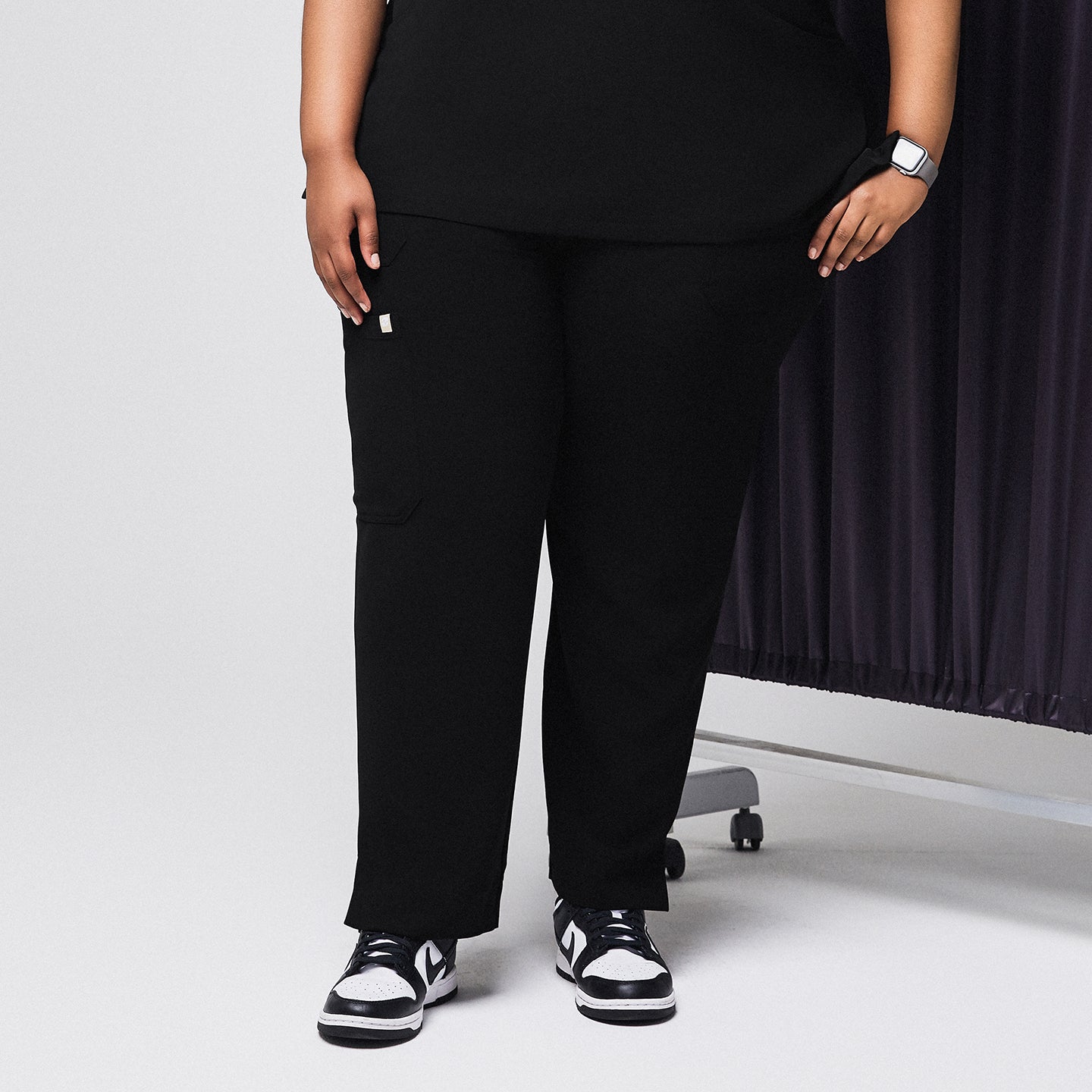 Image of Black scrub pants with split hem and side pocket, paired with black and white sneakers,Rich Black