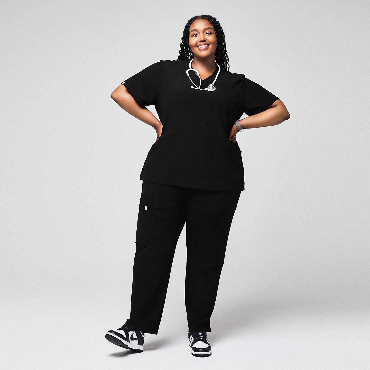 Image of Smiling woman wearing black scrubs with split hem pants and a stethoscope around her neck, paired with black and white sneakers,Rich-Black