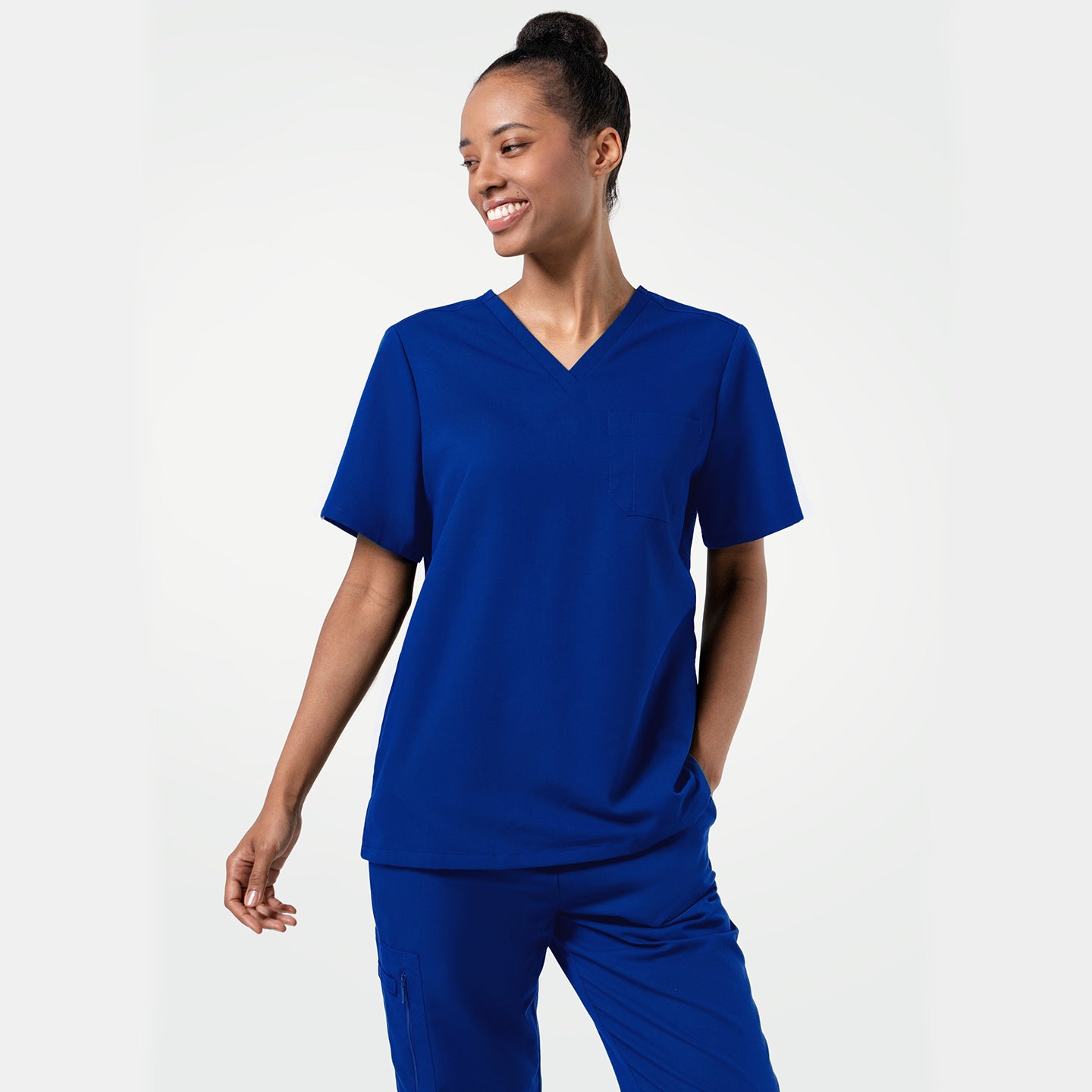 Image of Female model smiling while wearing the Women's Royal Blue 3-Pocket Scrub Top, with one hand in the pocket