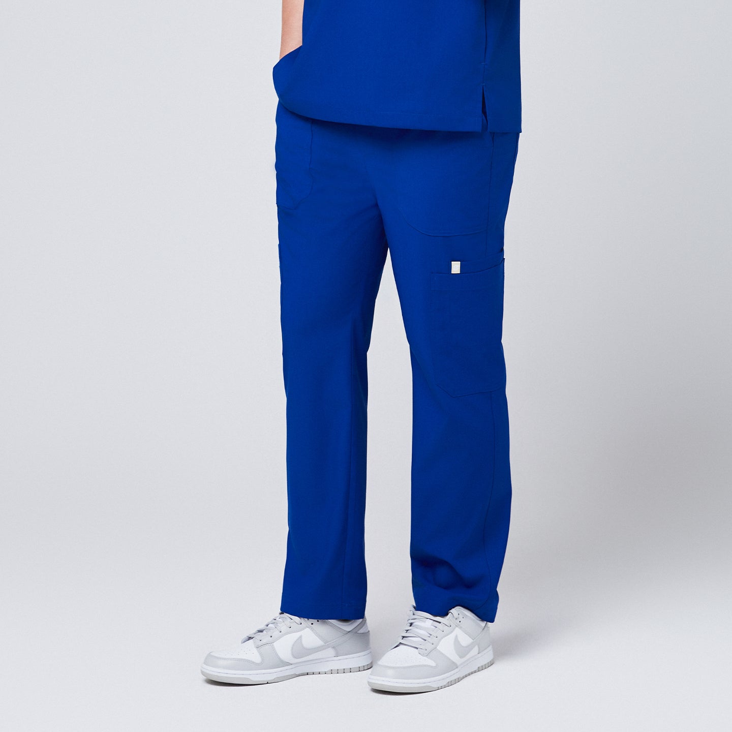 Close-up of royal blue 8-pocket straight scrub pants paired with white sneakers, showcasing functional pocket design,Royal Blue