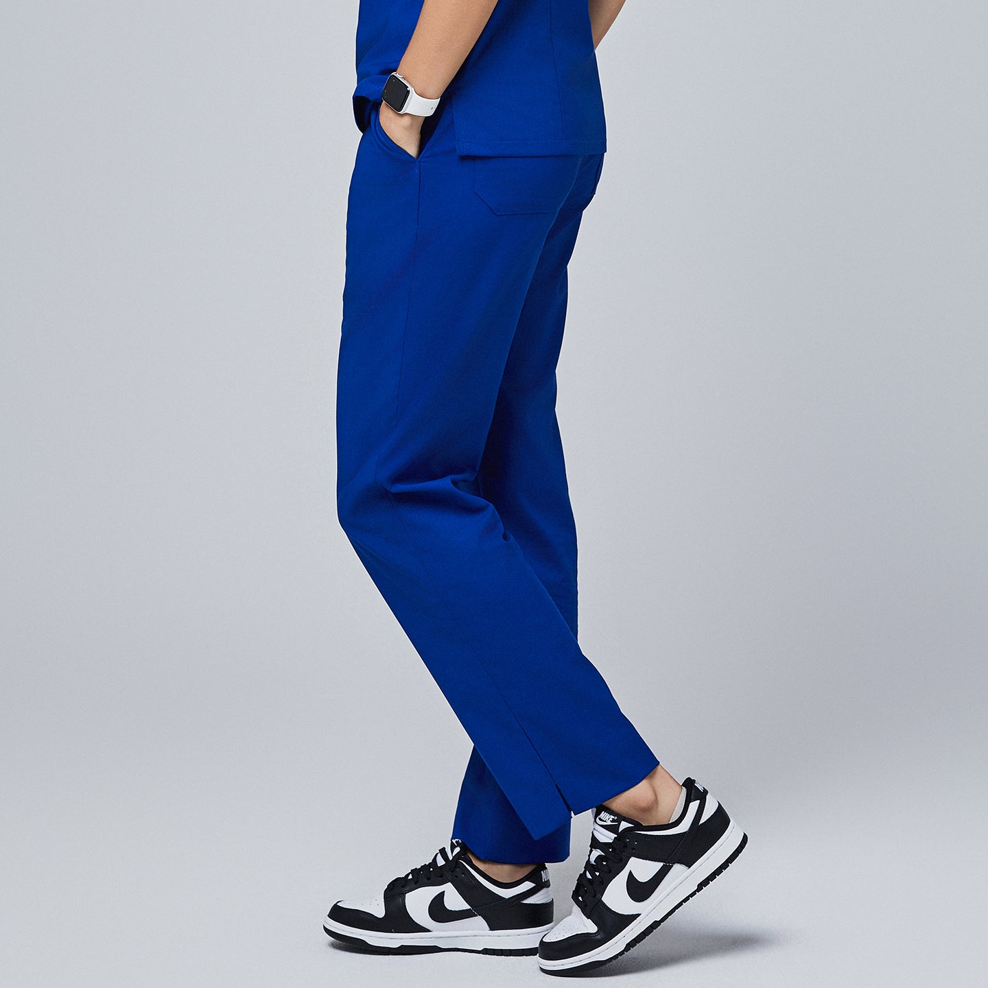 Image of Royal blue scrub pants with a split hem and functional zipper pockets, paired with black and white sneakers for a modern, professional look,Royal Blue