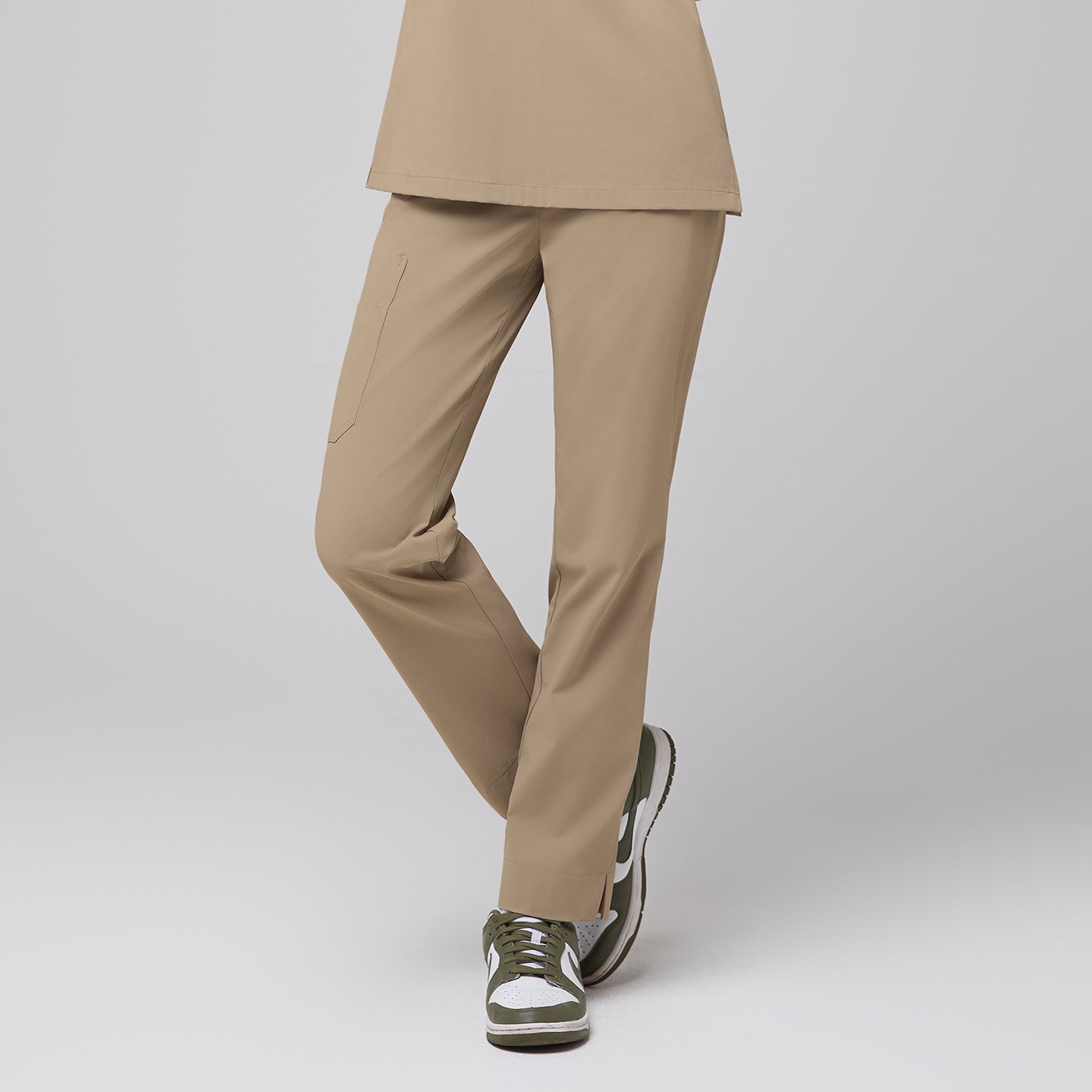 Front view of a woman wearing sand beige straight scrub pants with multiple pockets and a split hem, highlighting a comfortable fit and functional design for healthcare professionals,Sand beige