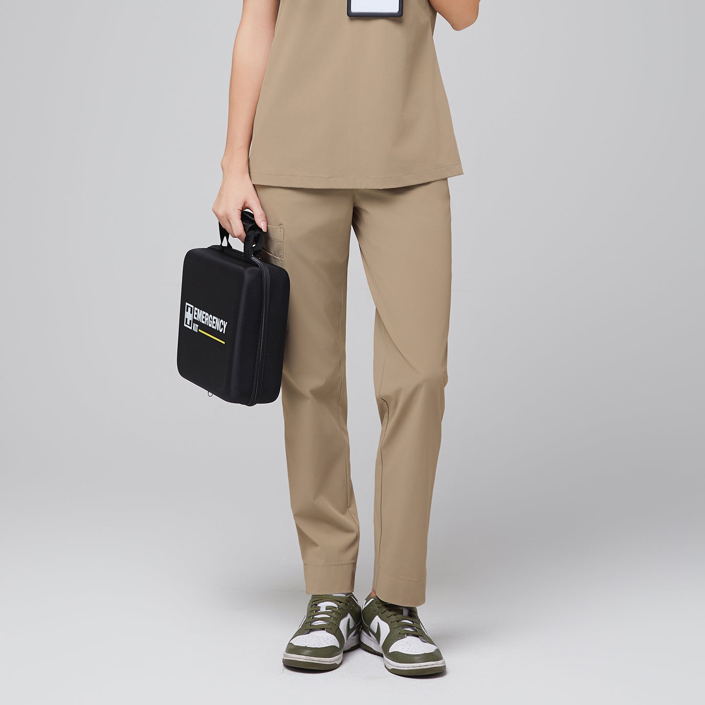 Image of Woman wearing sand beige cargo scrub pants and matching scrub top while holding a black medical kit, showcasing comfortable and functional healthcare apparel,Sand beige