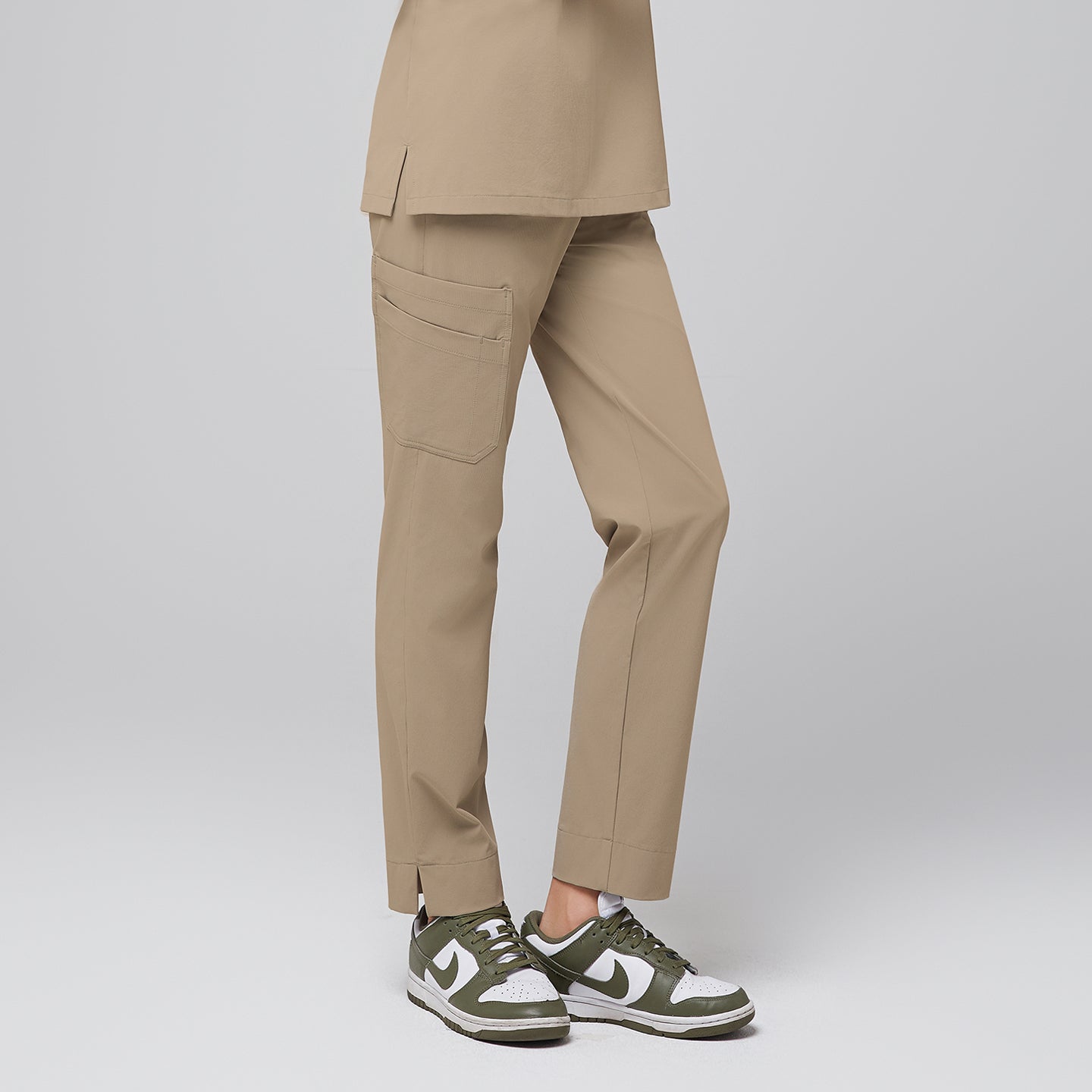 Image of Woman wearing sand beige straight scrub pants with multiple pockets and a split hem, highlighting a comfortable fit and functional design for healthcare professionals,Sand beige