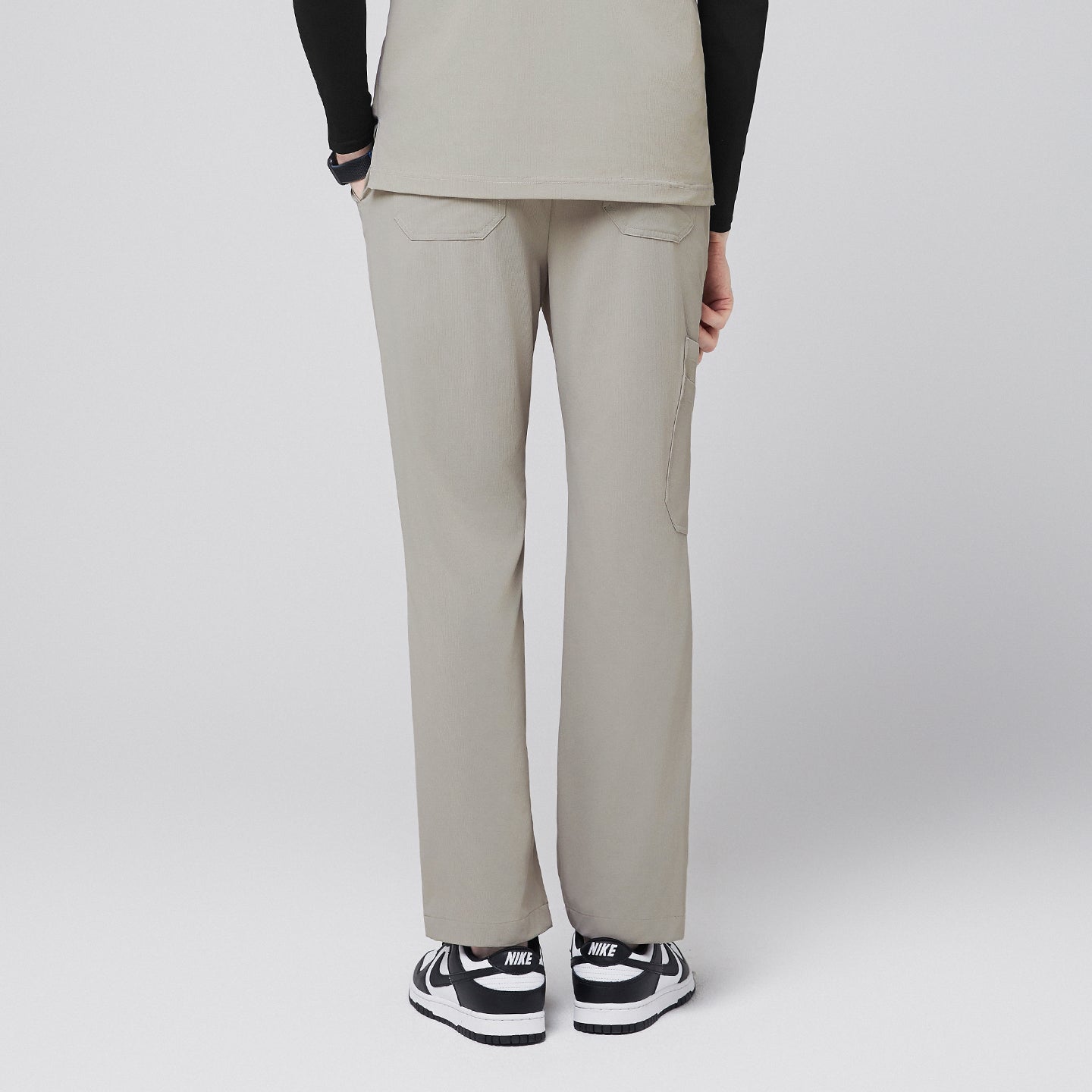 Image of Back view of sand khaki scrub pants featuring back pockets and a straight-leg fit, paired with black-and-white sneakers,Sand Khaki