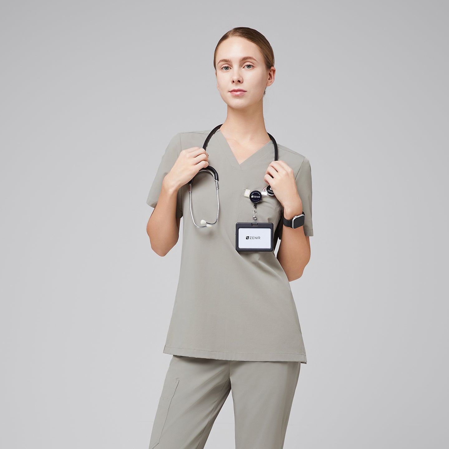 Image of Female healthcare professional wearing a sand khaki V-neck scrub top and pants with a stethoscope and name badge,Sand Khaki