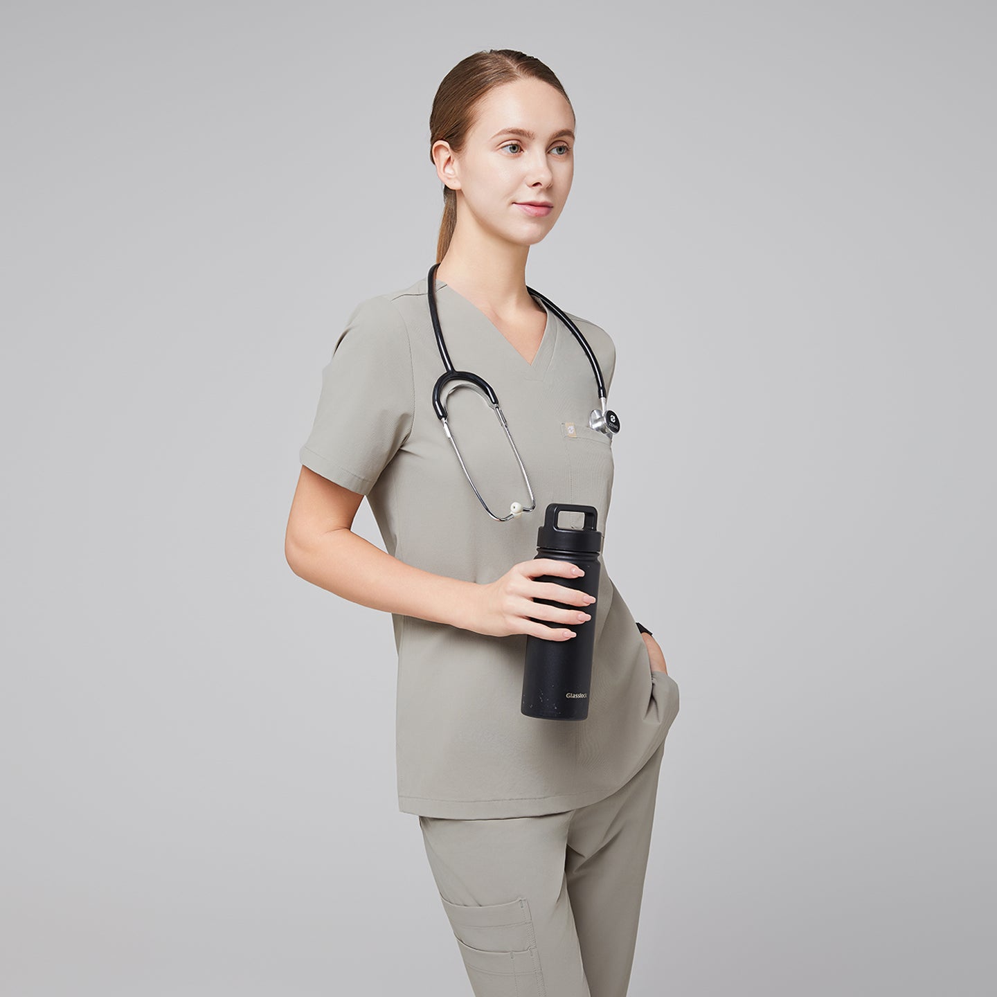 Image of Female healthcare professional in a sand khaki scrub set with a stethoscope, holding a black water bottle,Sand Khaki