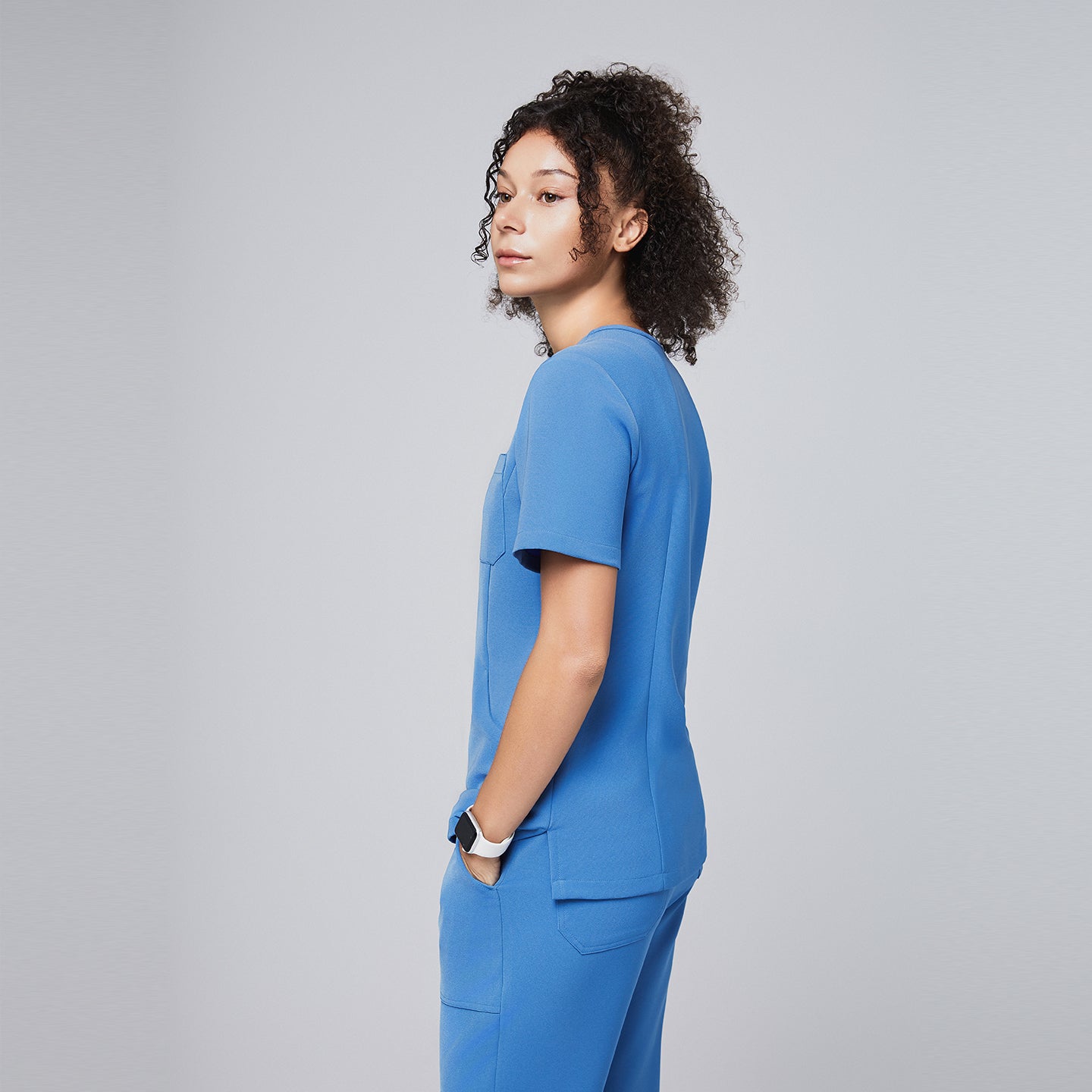 Woman wearing a sky-blue scrub set viewed from the side, highlighting the streamlined fit and practical pocket placement of the professional uniform,Sky Blue