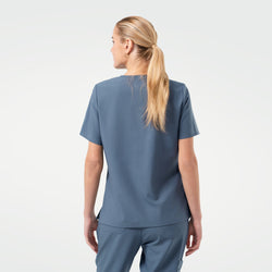 Image of Model is shown from the back, wearing a Smoky Blue scrub top paired with matching scrub pants. 