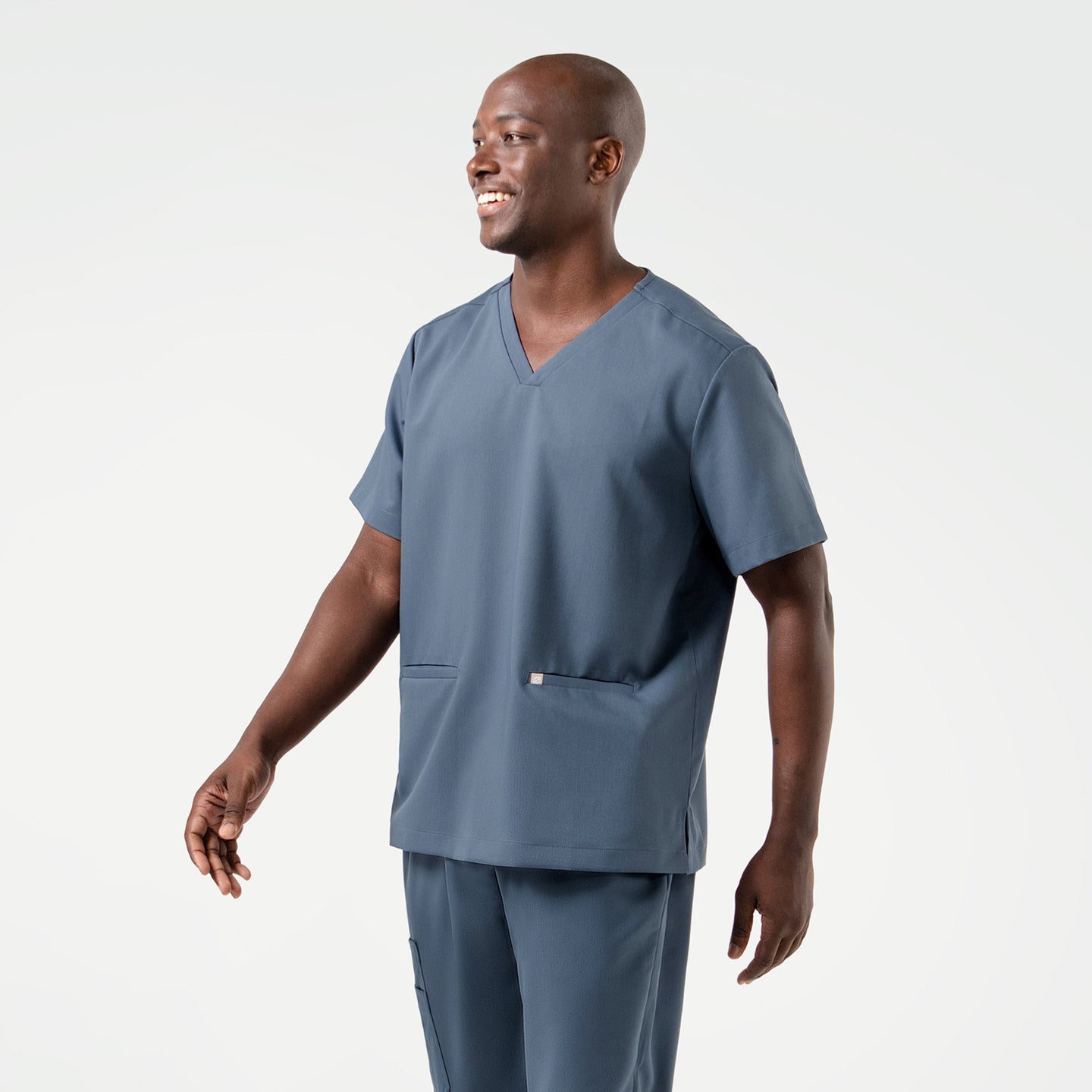 Image of Smiling confidently, the model showcases the Smoky Blue Double Pocket Scrub Top.