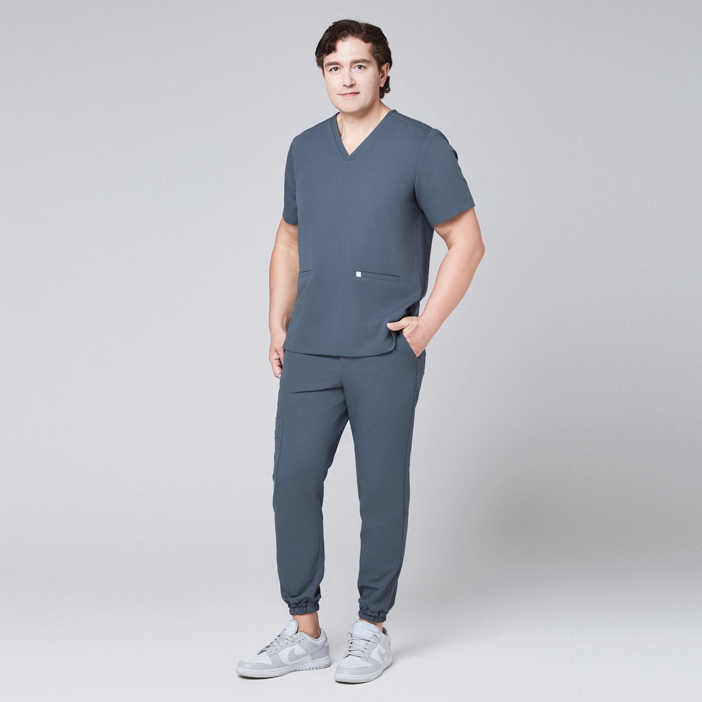 Image of Full-body view of a man in a smoky blue scrub set with jogger pants and a double-pocket V-neck top,Smoky Blue