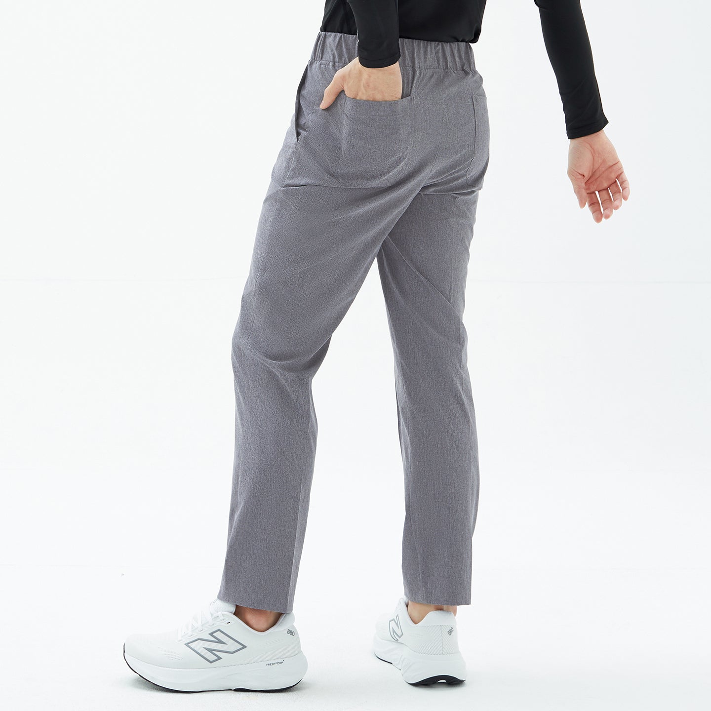 Male model showcasing the back view of Soft Gray Men’s Line Banding Pants, paired with a black top and white sneakers, with one hand in the pocket for a casual stance.
