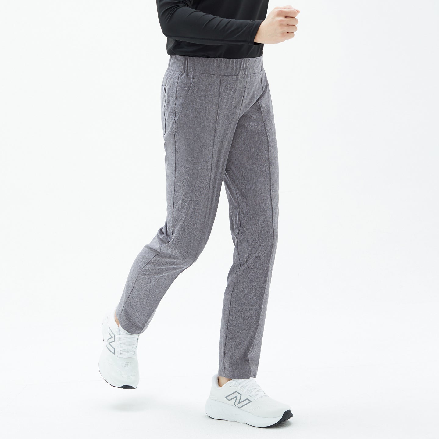 Male model in Soft Gray Men’s Line Banding Pants, captured mid-step in a walking pose, paired with a black top and white sneakers.
