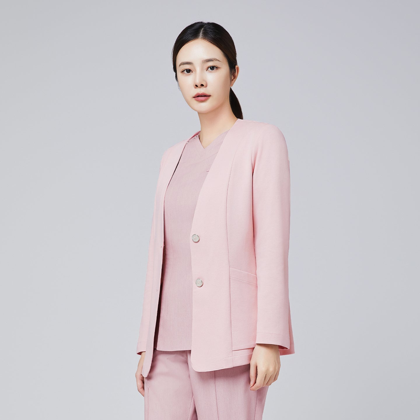 Image of A woman dressed in a soft pink comfort cardigan and matching trousers, styled with a sleek ponytail, posing confidently against a plain background,Soft Pink