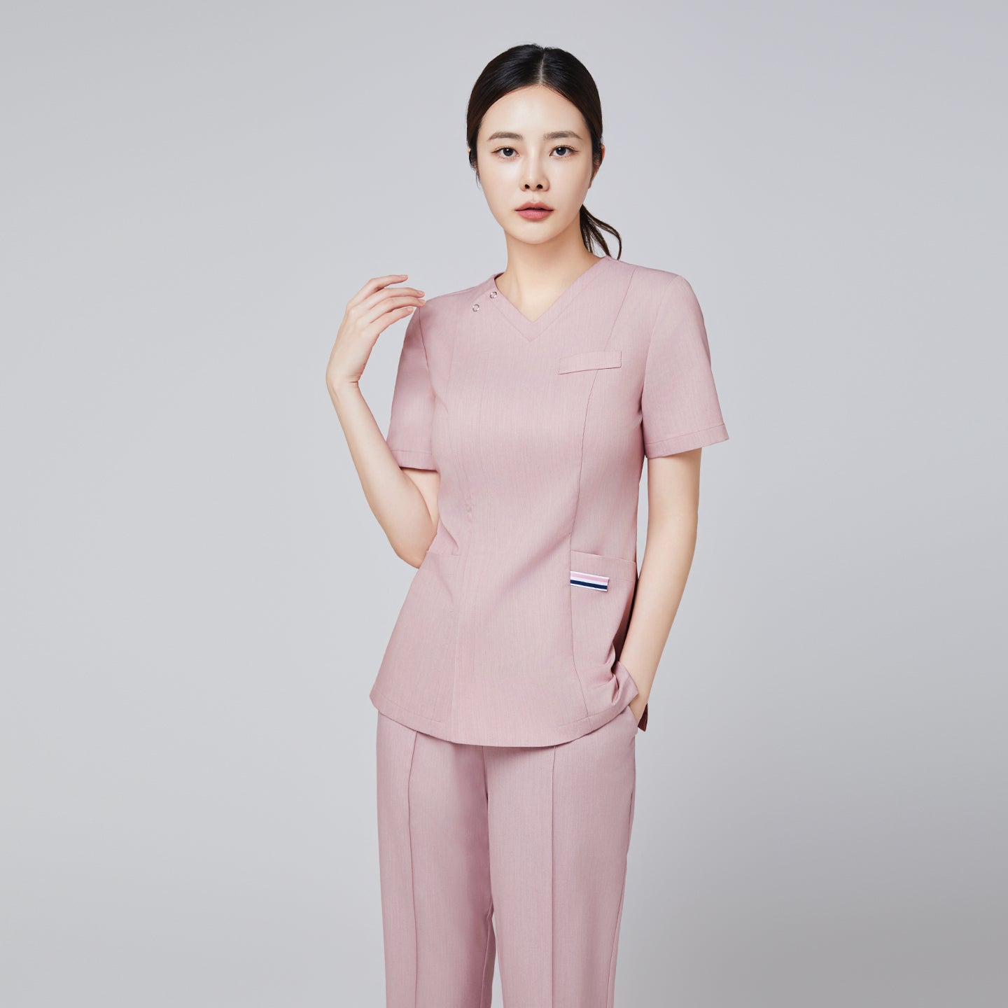 Image of full body shot of women wearing pink straight scrub pants with a line banding detail, with a matching soft pink scrub top and red sneakers,Soft pink