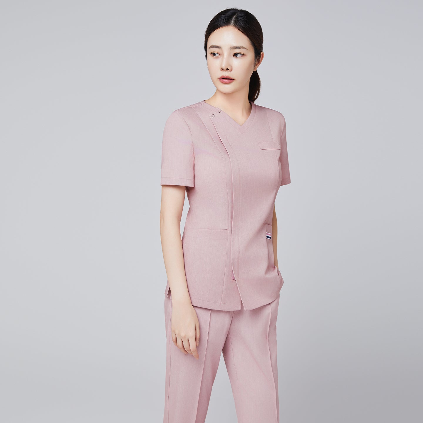 Image of full body shot of women wearing pink straight scrub pants with a line banding detail, with a matching soft pink scrub top and red sneakers,Soft pink