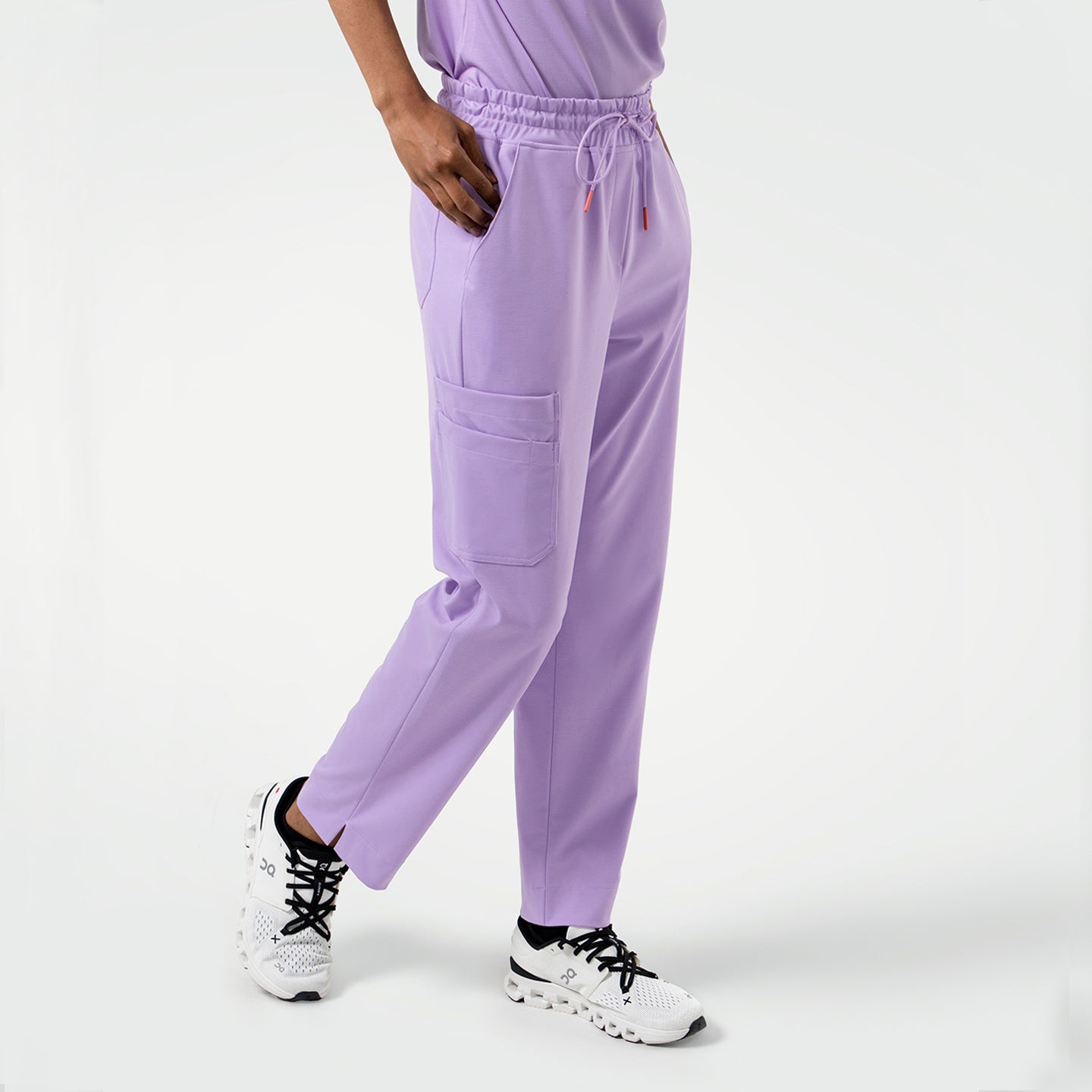 Image of Person wearing Straight Split Hem Scrub Pants in Lavender, standing with one leg slightly forward and a hand resting in the pocket.