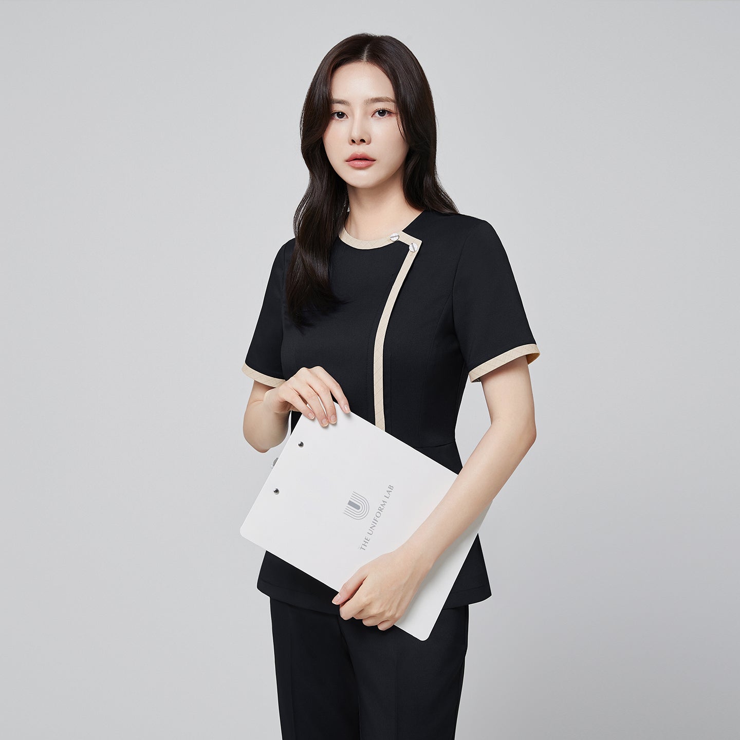 Image of Front angle of TUL NS-175 Women’s Check Beige Round Collar Scrub Top in Stretch Black, highlighting a tailored waist and short sleeves.