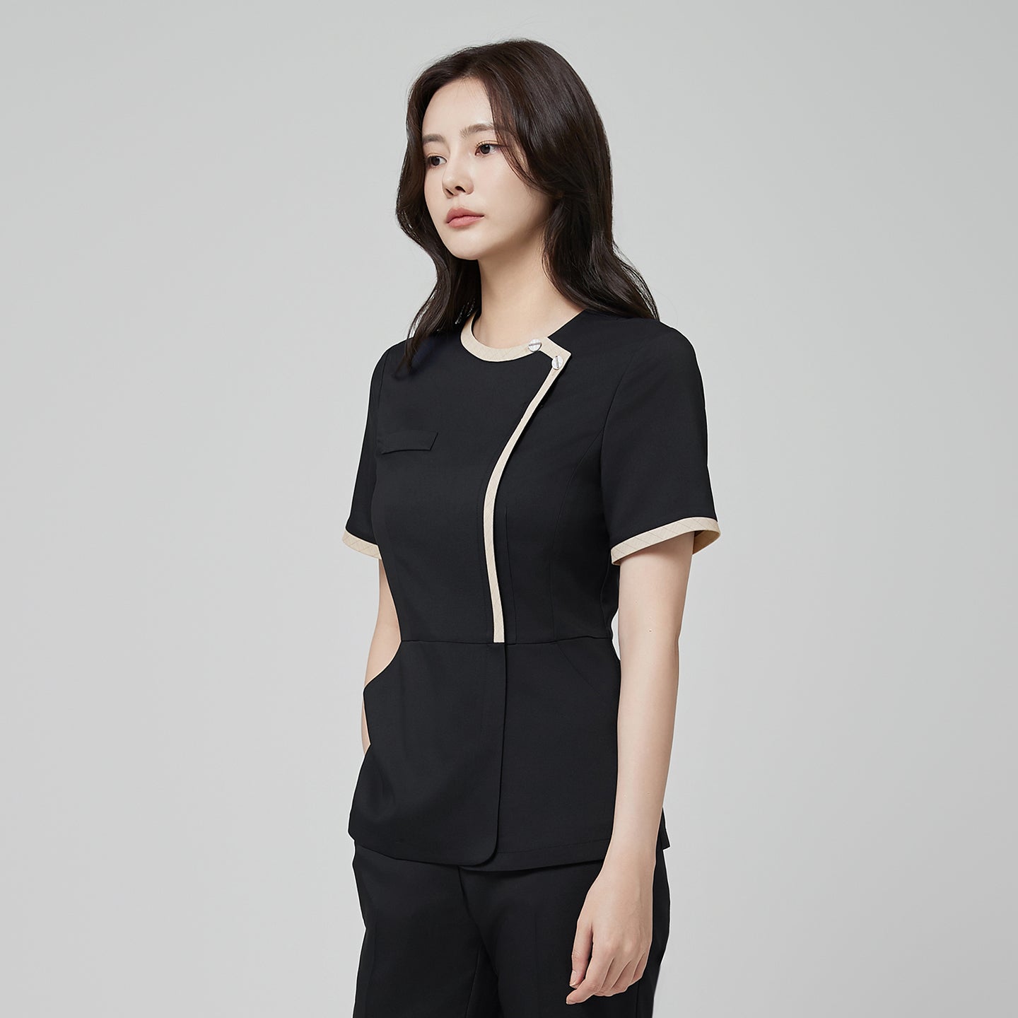 Side angle of TUL NS-175 Stretch Black scrub top, showcasing a round beige collar, subtle check accents, and a comfortable fit.