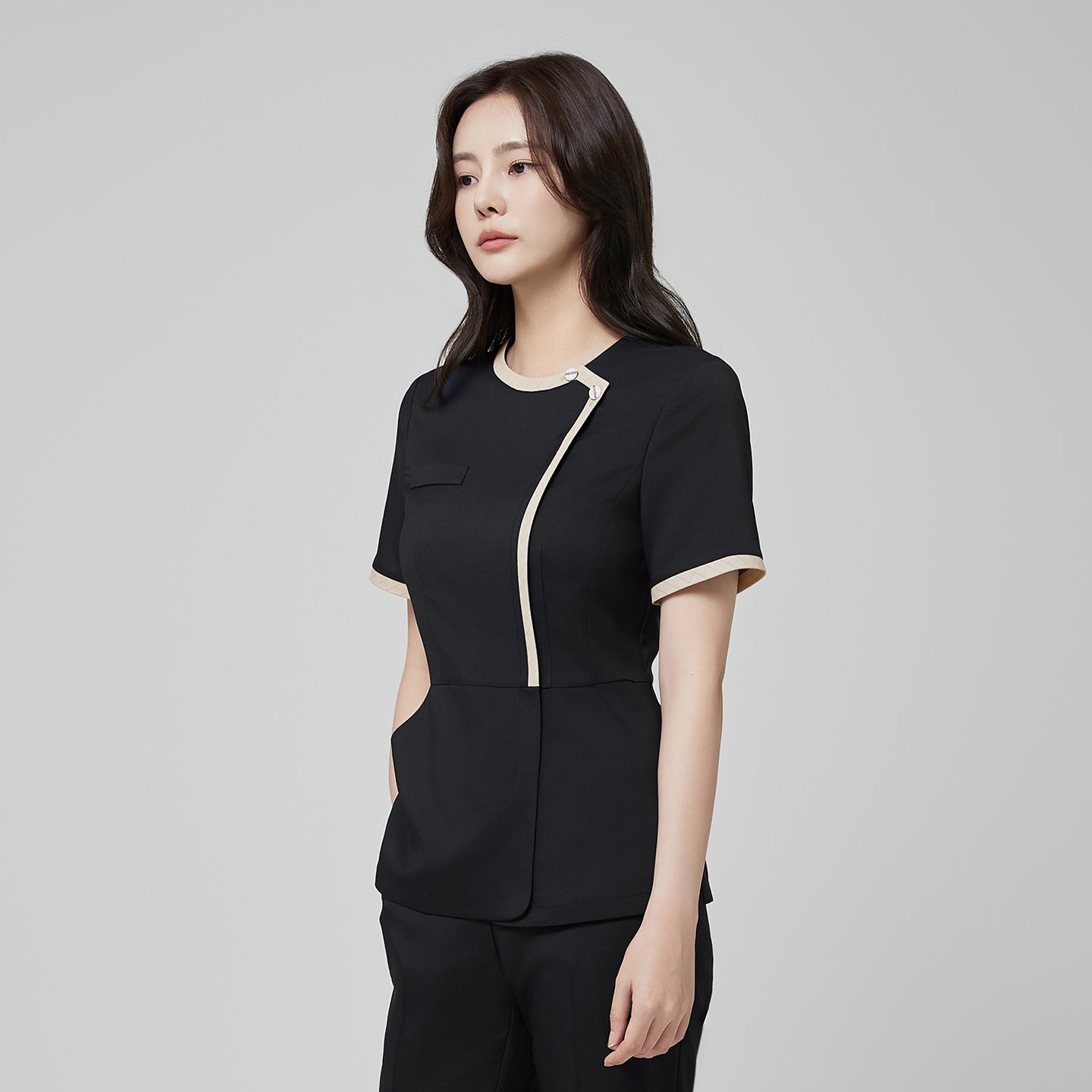 Image of Side angle of TUL NS-175 Stretch Black scrub top, showcasing a round beige collar, subtle check accents, and a comfortable fit.