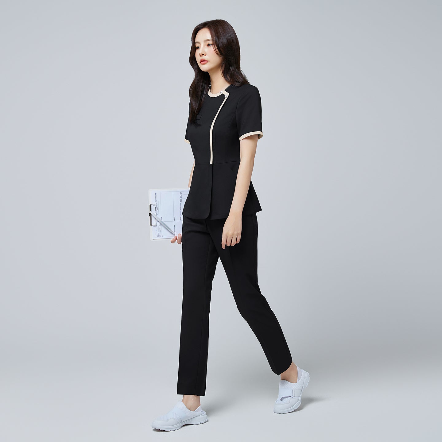 Full-length view of TUL NS-175 Stretch Black scrub top with beige accents, paired with matching pants for a cohesive professional outfit.
