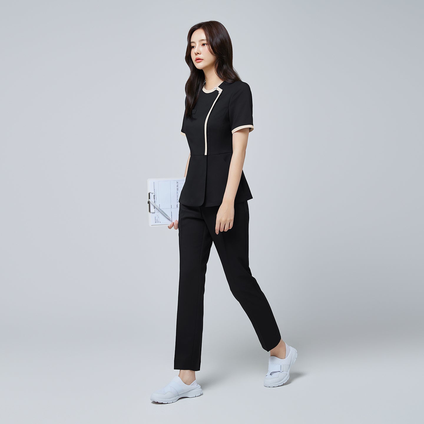 Image of Full-length view of TUL NS-175 Stretch Black scrub top with beige accents, paired with matching pants for a cohesive professional outfit.