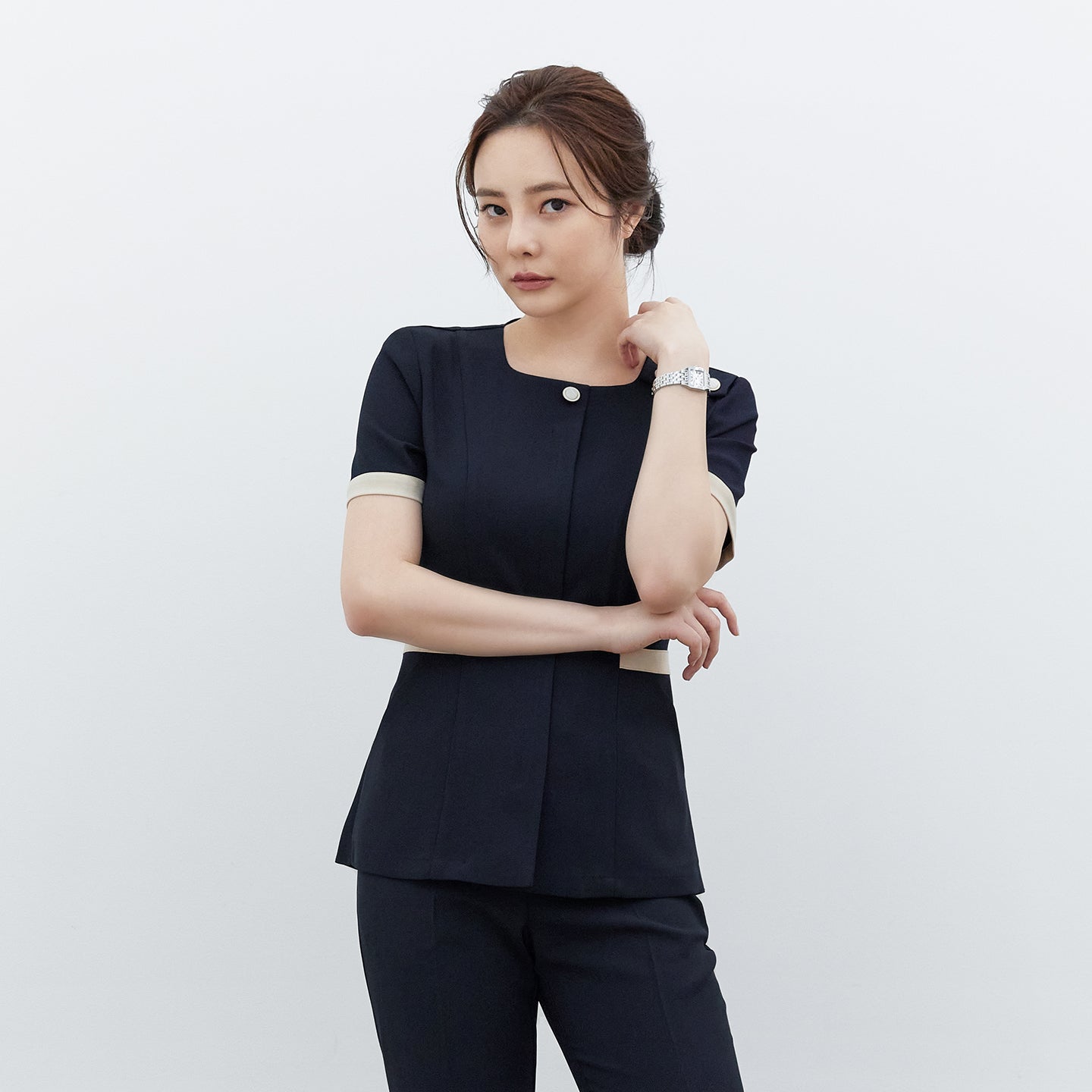 Model crossing arms in TUL NCS-01 Stretch Navy scrub top, featuring contrast trim on sleeves and waist for a modern, polished style.