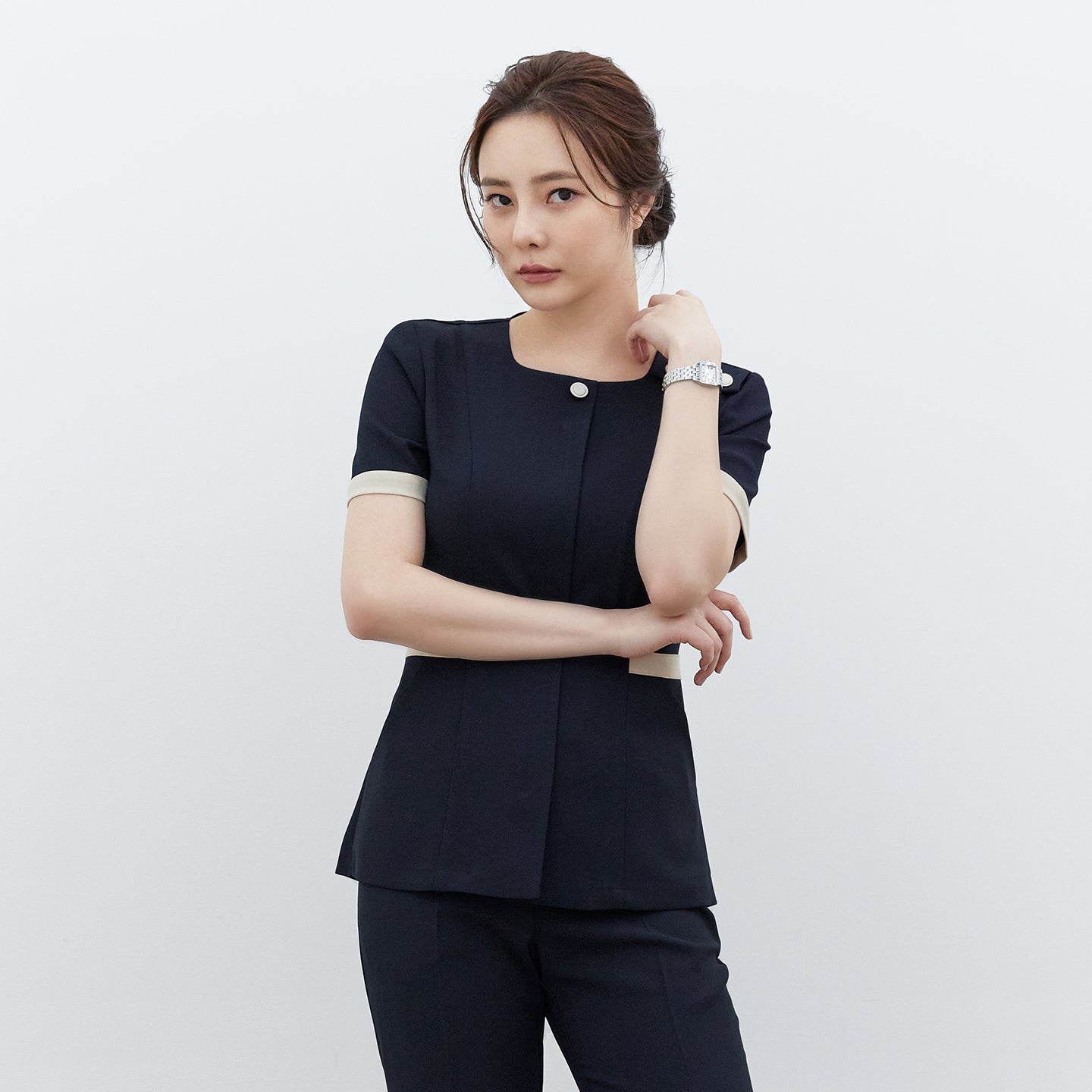 Image of Model crossing arms in TUL NCS-01 Stretch Navy scrub top, featuring contrast trim on sleeves and waist for a modern, polished style.