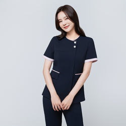 Image of Model wearing TUL NCS-04 Women’s Blush Edge Scrub Top in Stretch Navy, smiling with arms crossed, emphasizing pink sleeve trim.