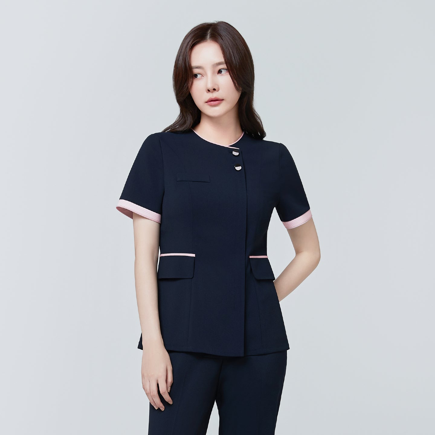 Image of Angled shot of TUL NCS-04 Stretch Navy scrub top with pink edging, showcasing button closures and structured waist pockets.