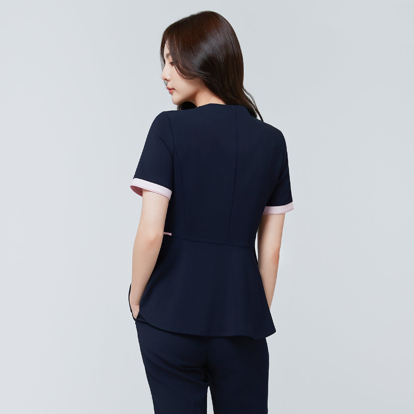 Back view of TUL NCS-04 Women’s Blush Edge Scrub Top in Stretch Navy, featuring a gently flared hem and contrast pink cuffs.