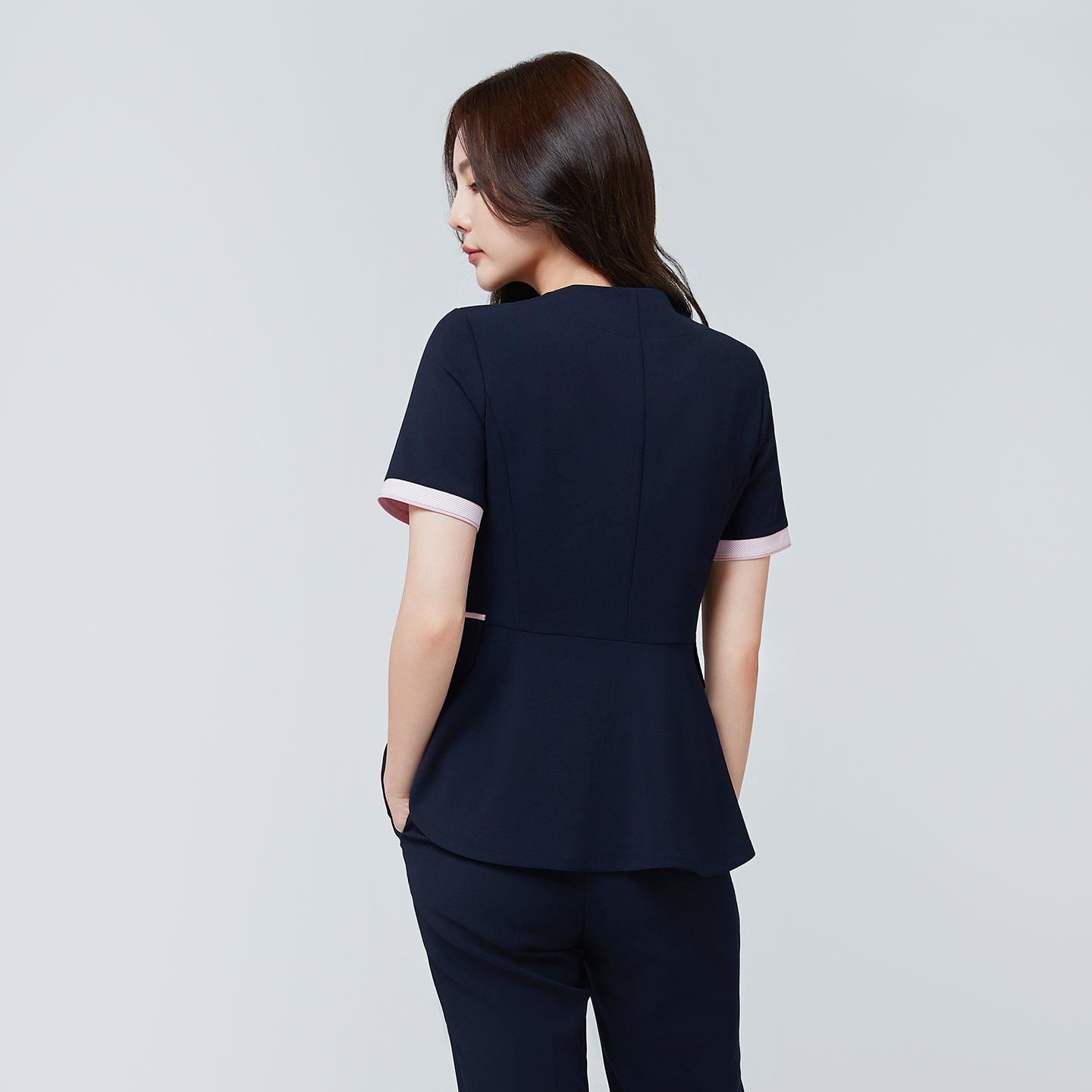 Image of Back view of TUL NCS-04 Women’s Blush Edge Scrub Top in Stretch Navy, featuring a gently flared hem and contrast pink cuffs.