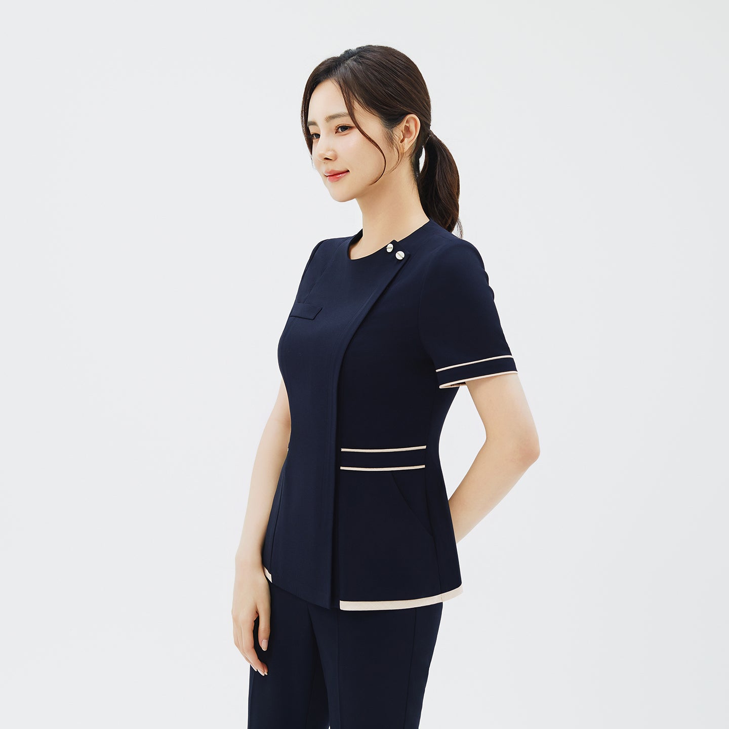 Side angle of TUL NCS-07 Women's Ivory Dual Tone Scrub Top in Stretch Navy, emphasizing the comfortable stretch fabric and refined silhouette.