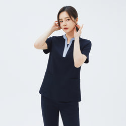Image of Model adjusting her hair while wearing TUL NS-179 Stretch Navy scrub top, highlighting the contrasting V-neck detail and short sleeves.