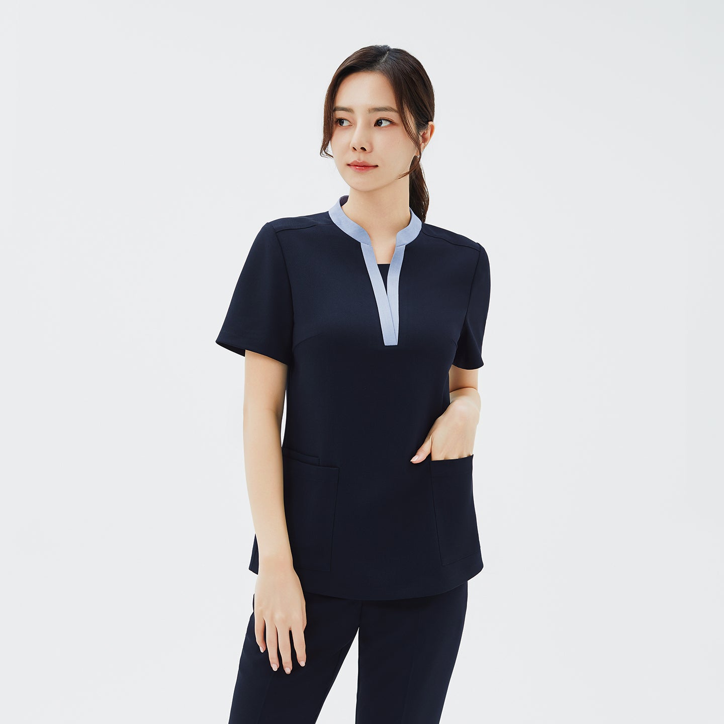 Front view of TUL NS-179 Women's V-Stretch Color Scrub Top in Stretch Navy, featuring a contrasting light blue neckline and roomy front pockets.