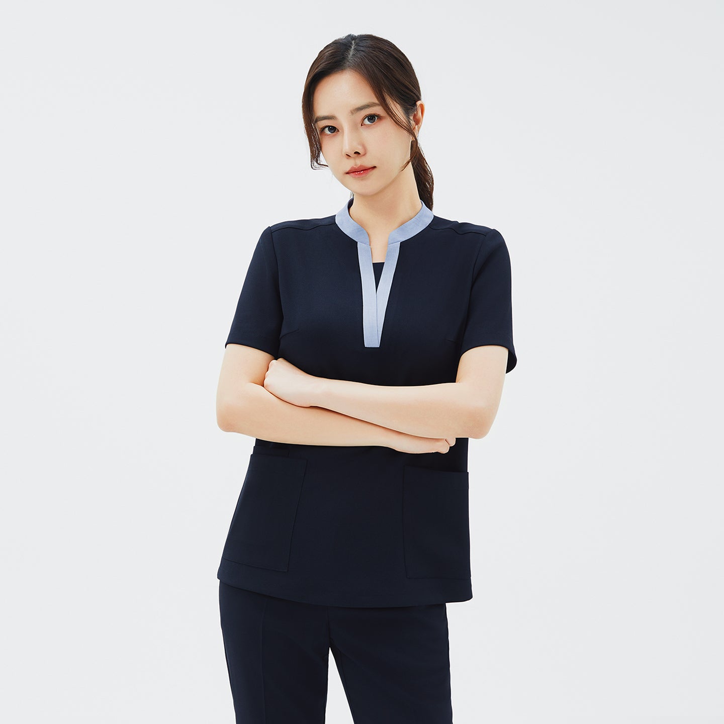 Image of Model wearing TUL NS-179 Women's V-Stretch Color Scrub Top in Stretch Navy, with arms crossed to emphasize a tailored fit and color-accented neckline.