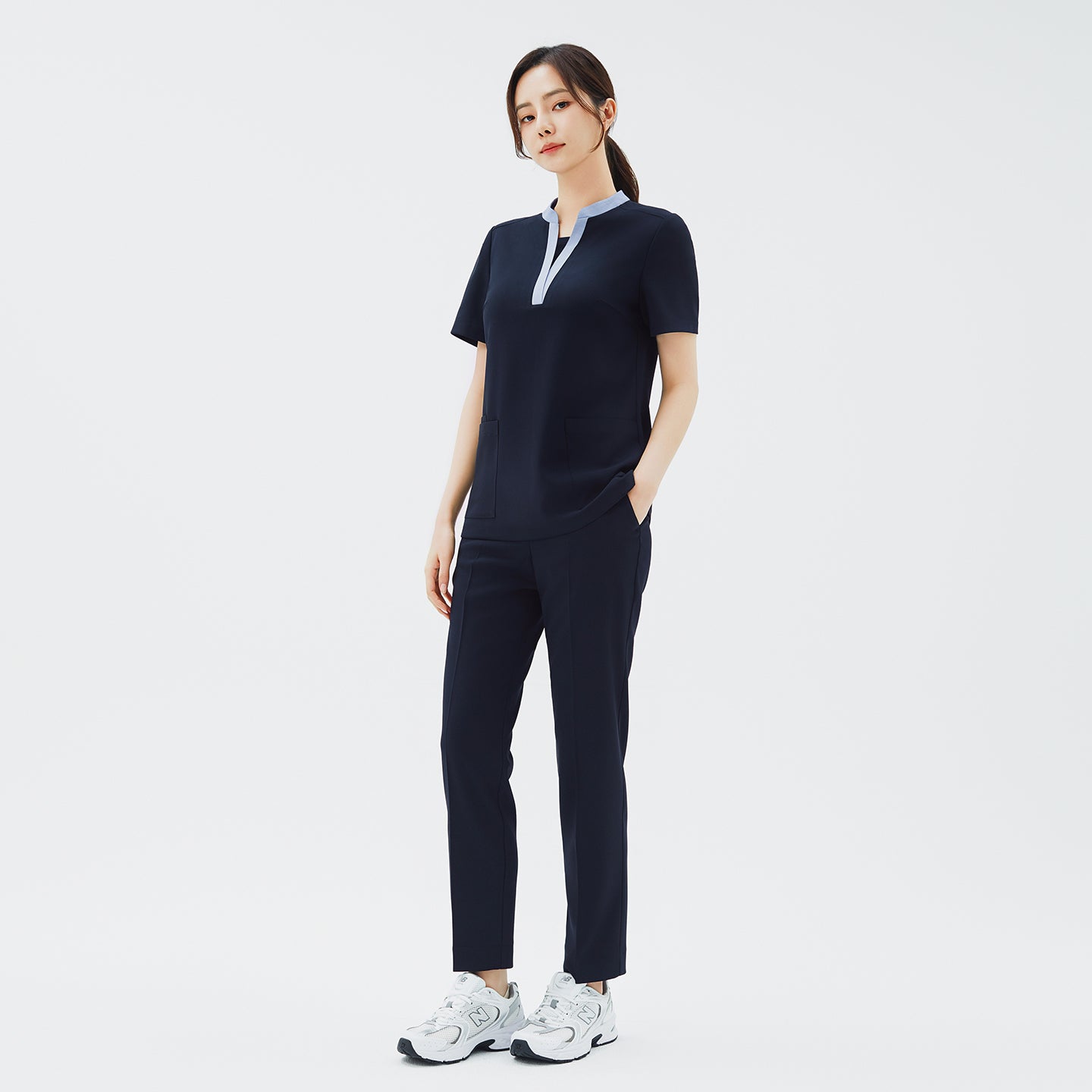 Model wearing TUL Women's Style Pants in Stretch Navy, featuring a refined silhouette and practical pockets for healthcare professionals.