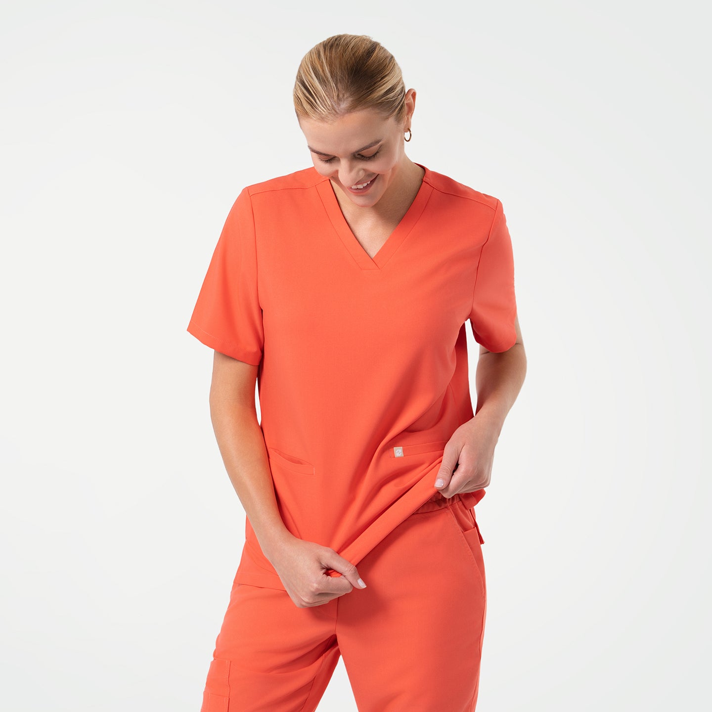 Image of The Tiger Orange Double Pocket Scrub Top features a vibrant orange hue that radiates energy and warmth.